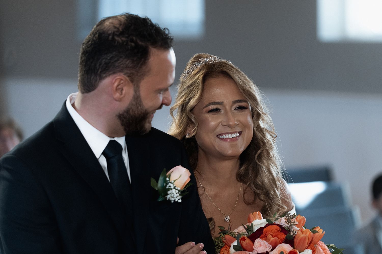 Wedding celebration with orange floral arrangements and formal attire.