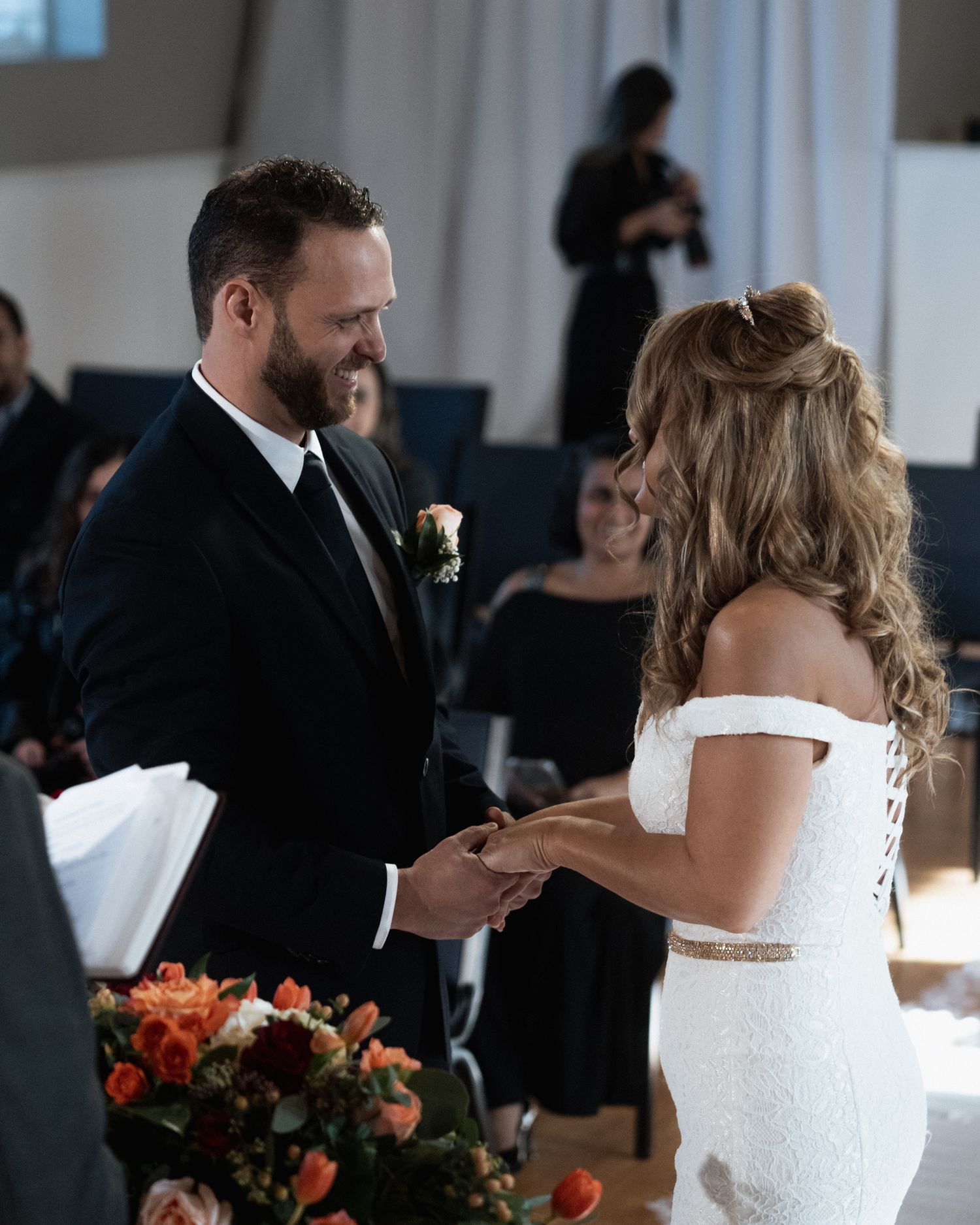 Elegant wedding ceremony with floral arrangements visible during ring exchange.