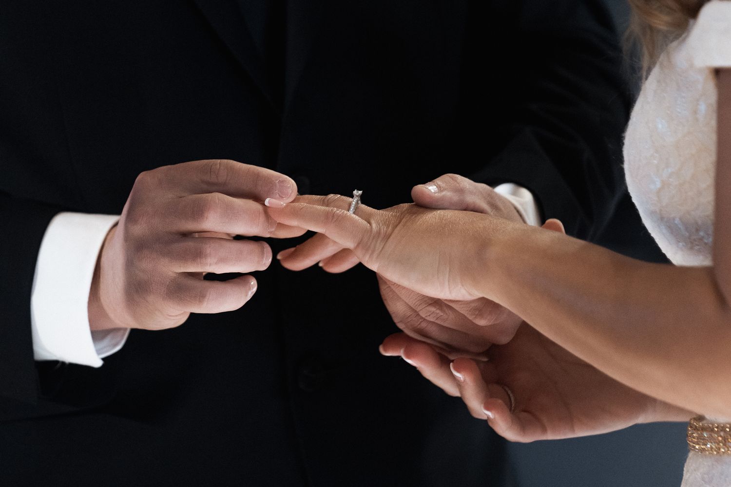 Close-up of hands exchanging wedding rings during an intimate ceremony.