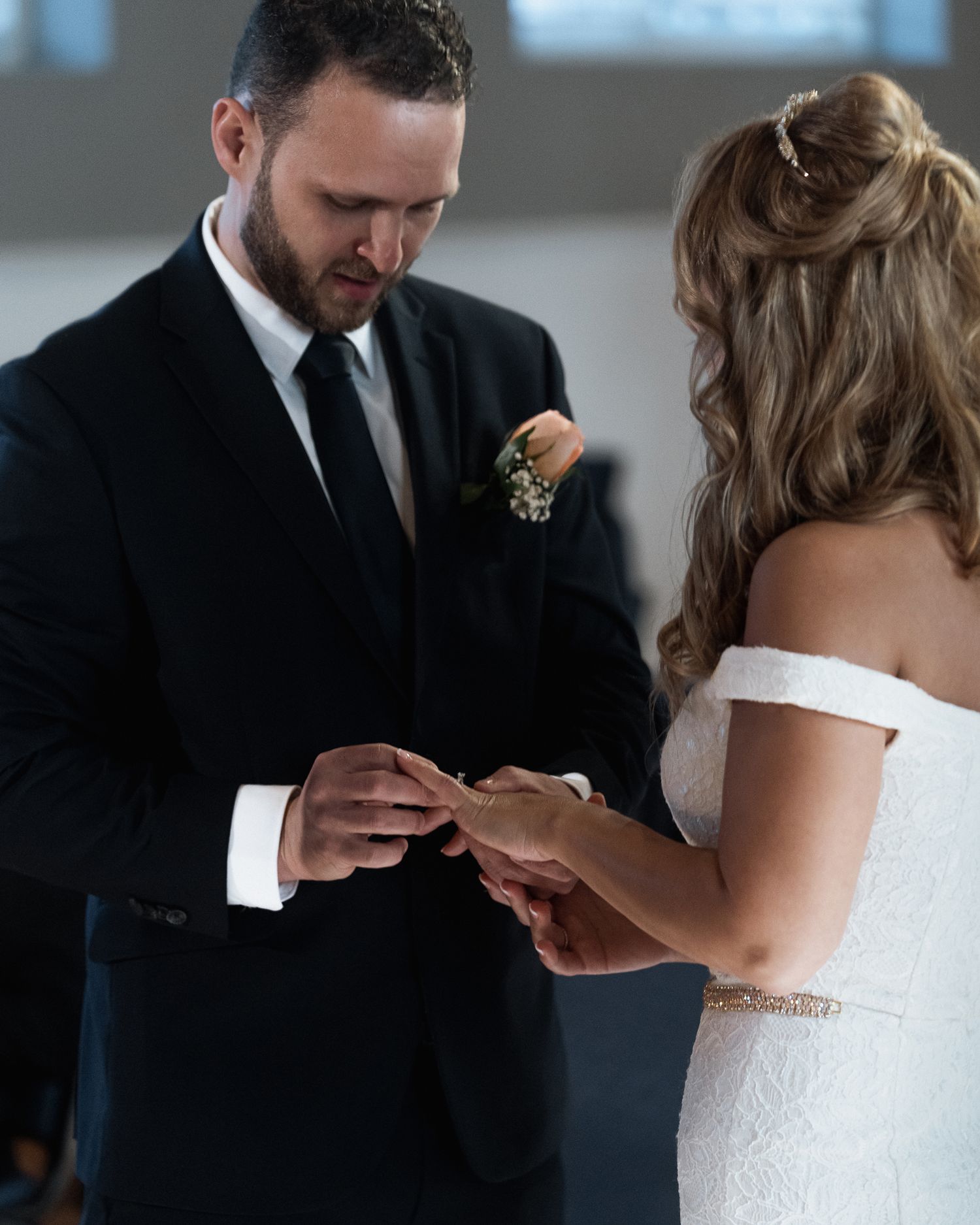 Bride and groom performing traditional ring exchange at indoor wedding ceremony.