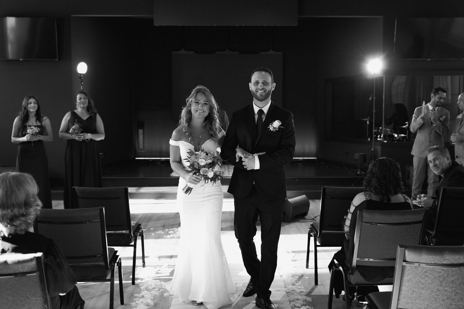 Black and white wedding ceremony photo in a dimly lit venue.
