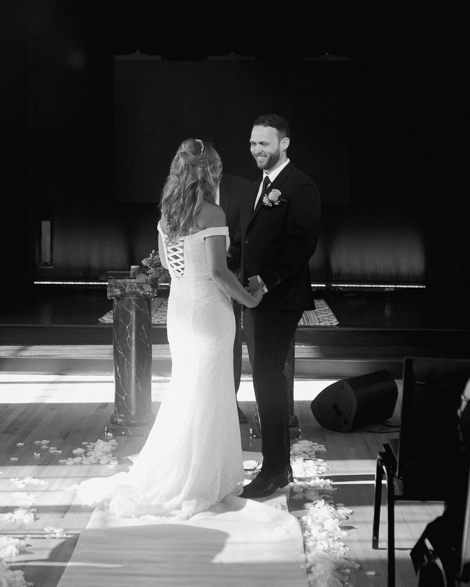 Black and white wedding ceremony shot showing a bride's flowing dress train.