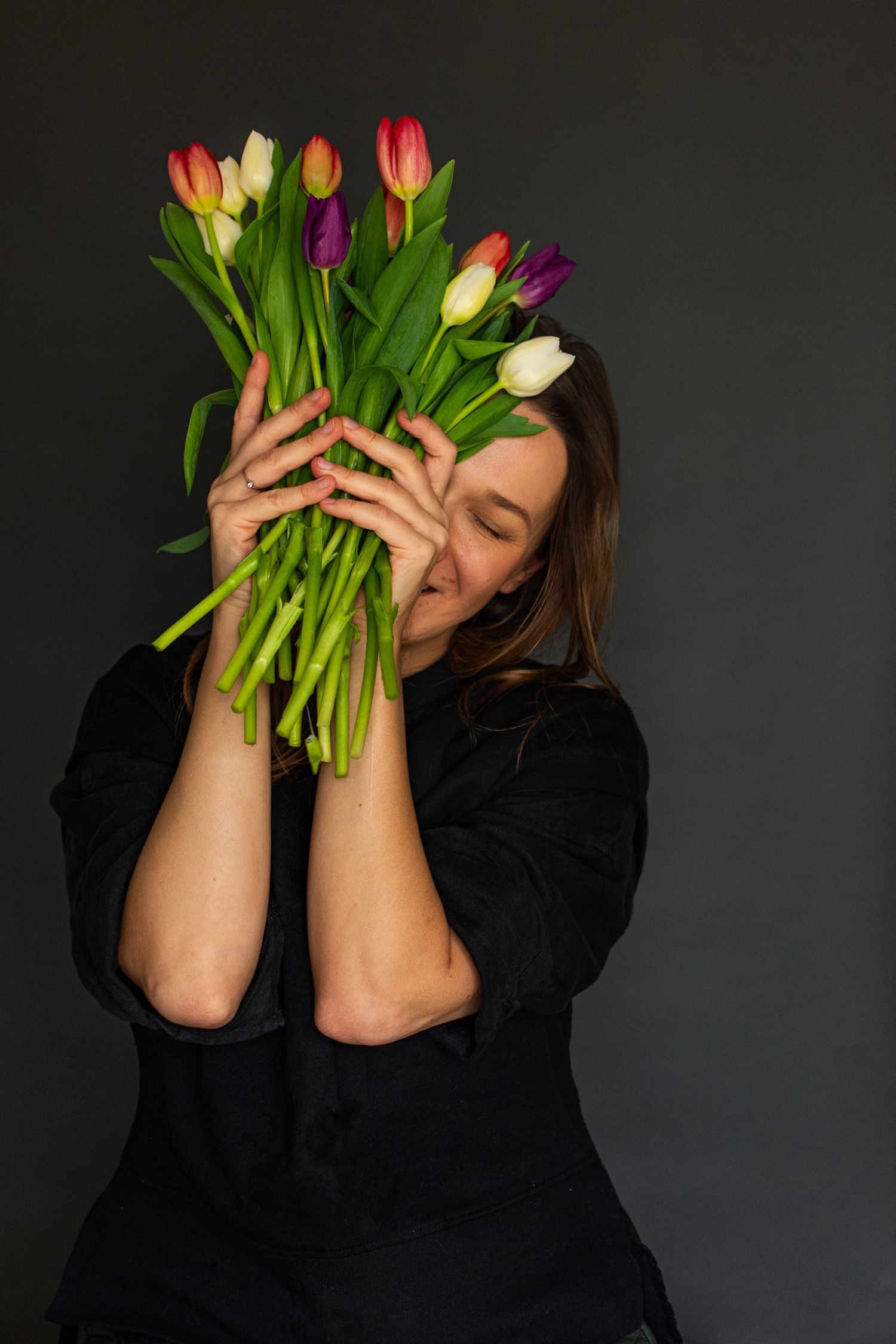 A woman lifting up the bouquet of tulips in Cambridge studio, UK