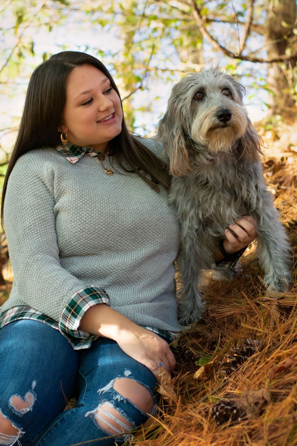 A happy grey terrier and its owner share a tender moment among autumn leaves.