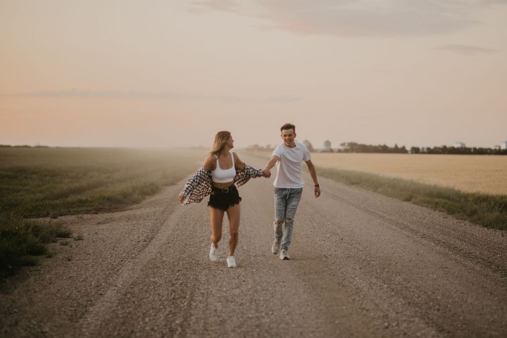 Two people joyfully running together on a country road at dusk.