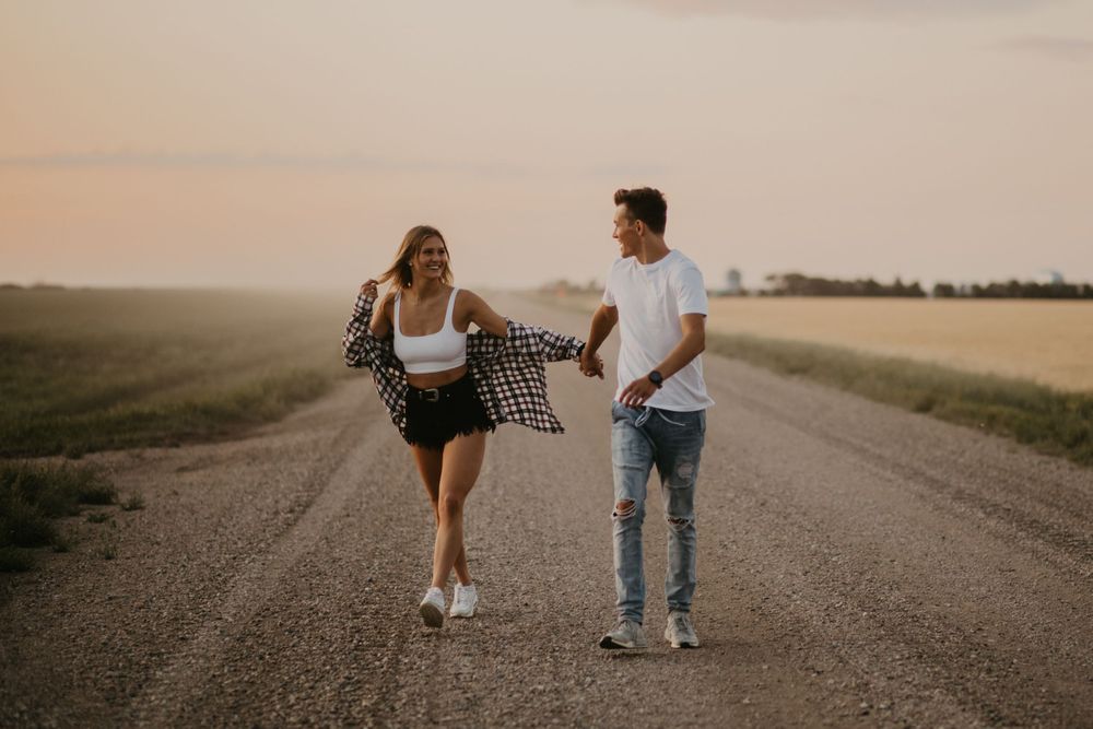 A couple walks together on a countryside road during golden hour.