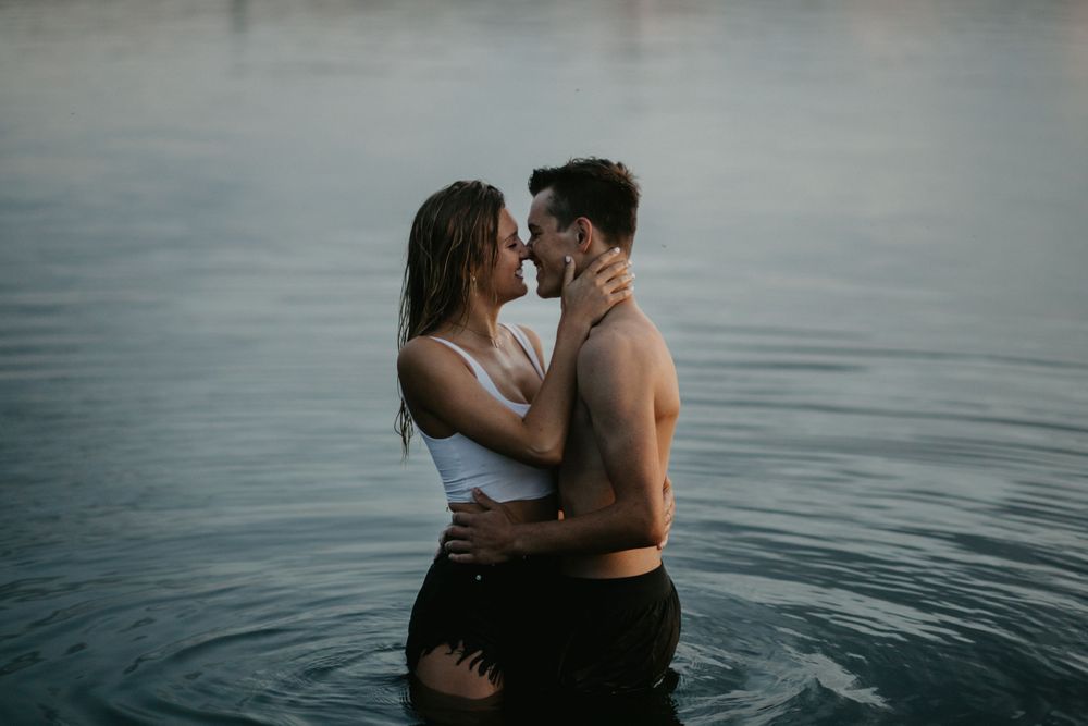 A tender moment captured between two people standing in tranquil waters at dusk.