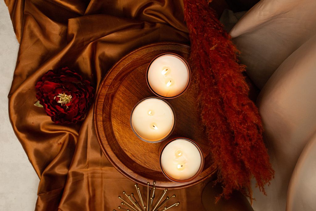 Three luxurious candles on top of a silk fabric