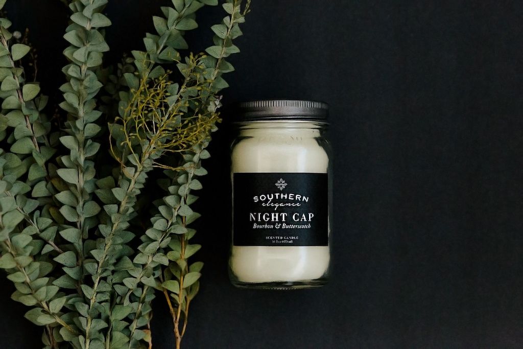Soy wax candle with greenery on a black background