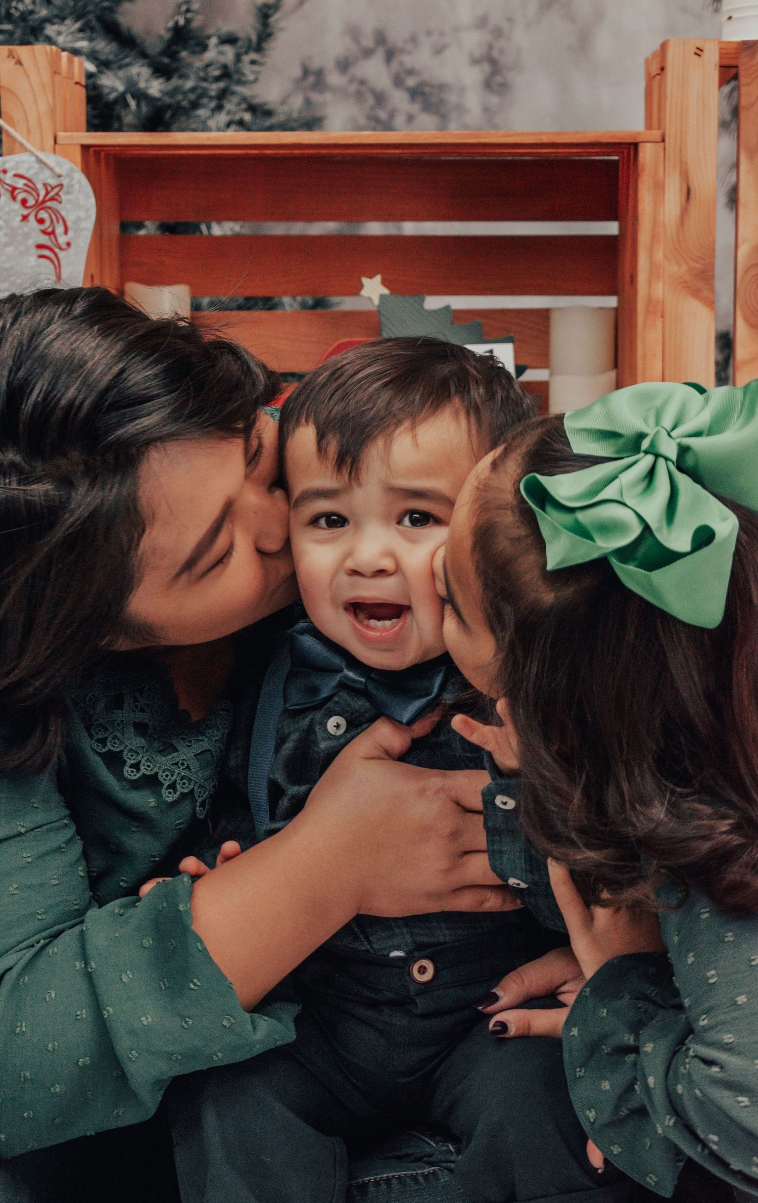 Sweet candid family moment captured with matching green outfits in indoor portrait setting.