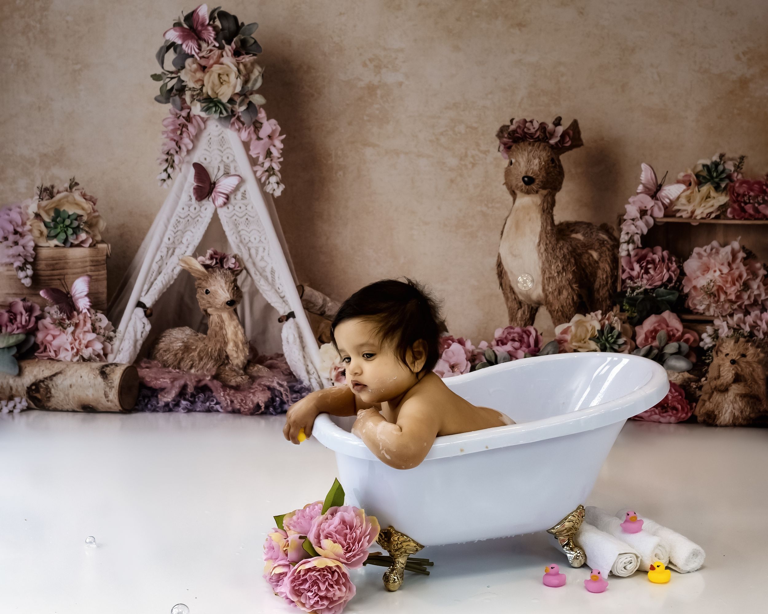 A vintage-style bath setup with pink roses, floral decorations and a white clawfoot tub.