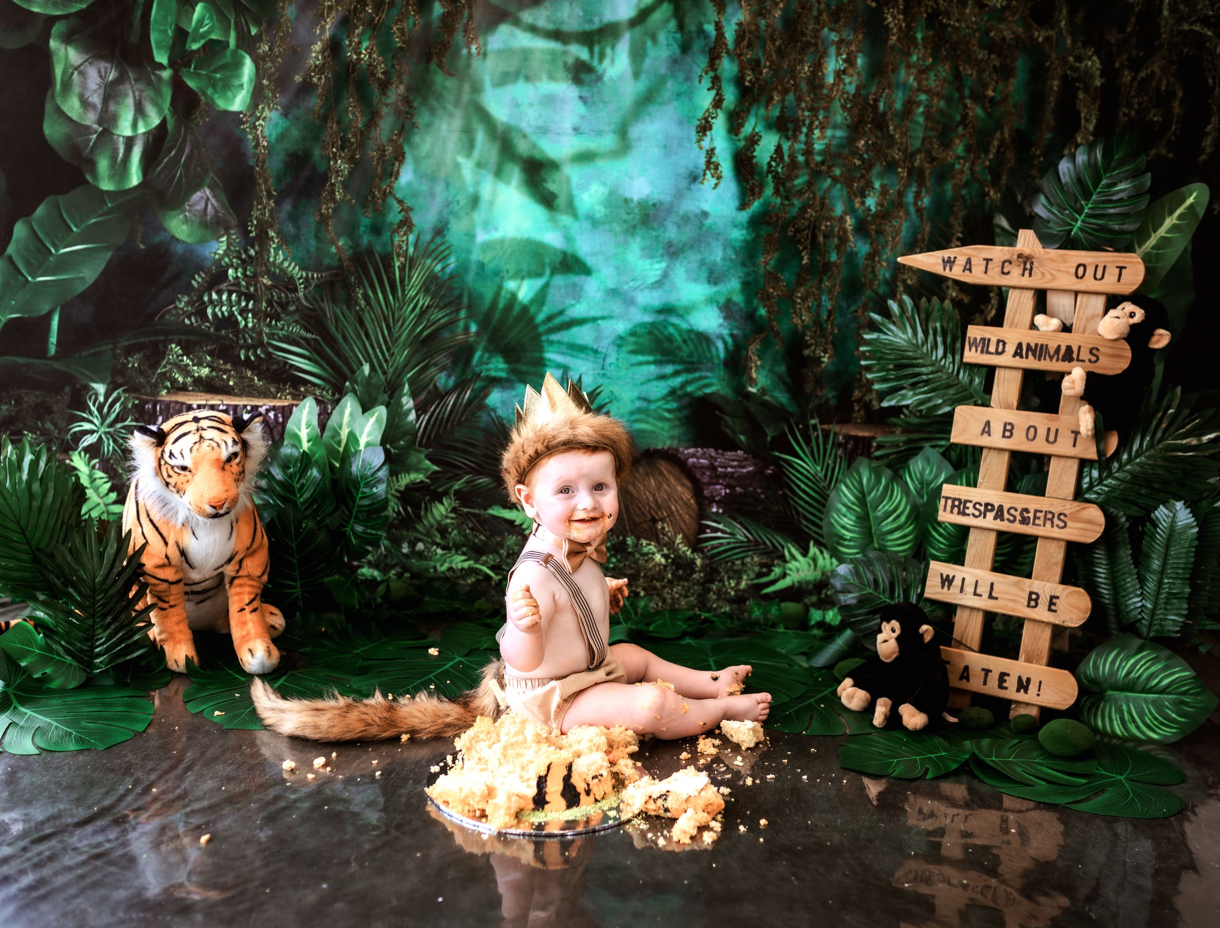 A jungle-themed photo setup with a plush tiger, wooden signpost, and tropical greenery in ethereal turquoise lighting.