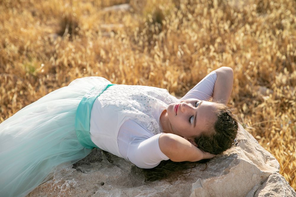 A beautiful girl lying on a rock in a golden field