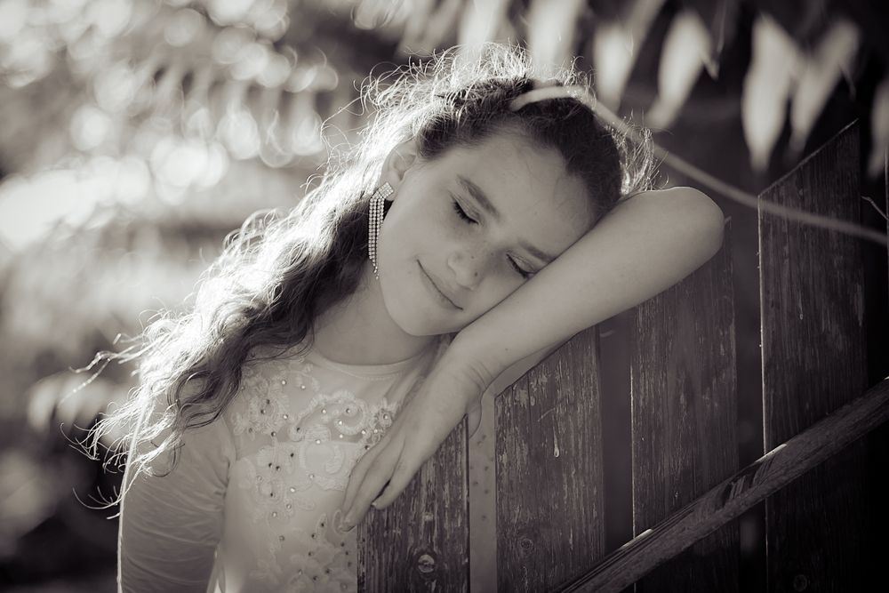 a beautiful girl leaning Leaning on the fence with eyes closed