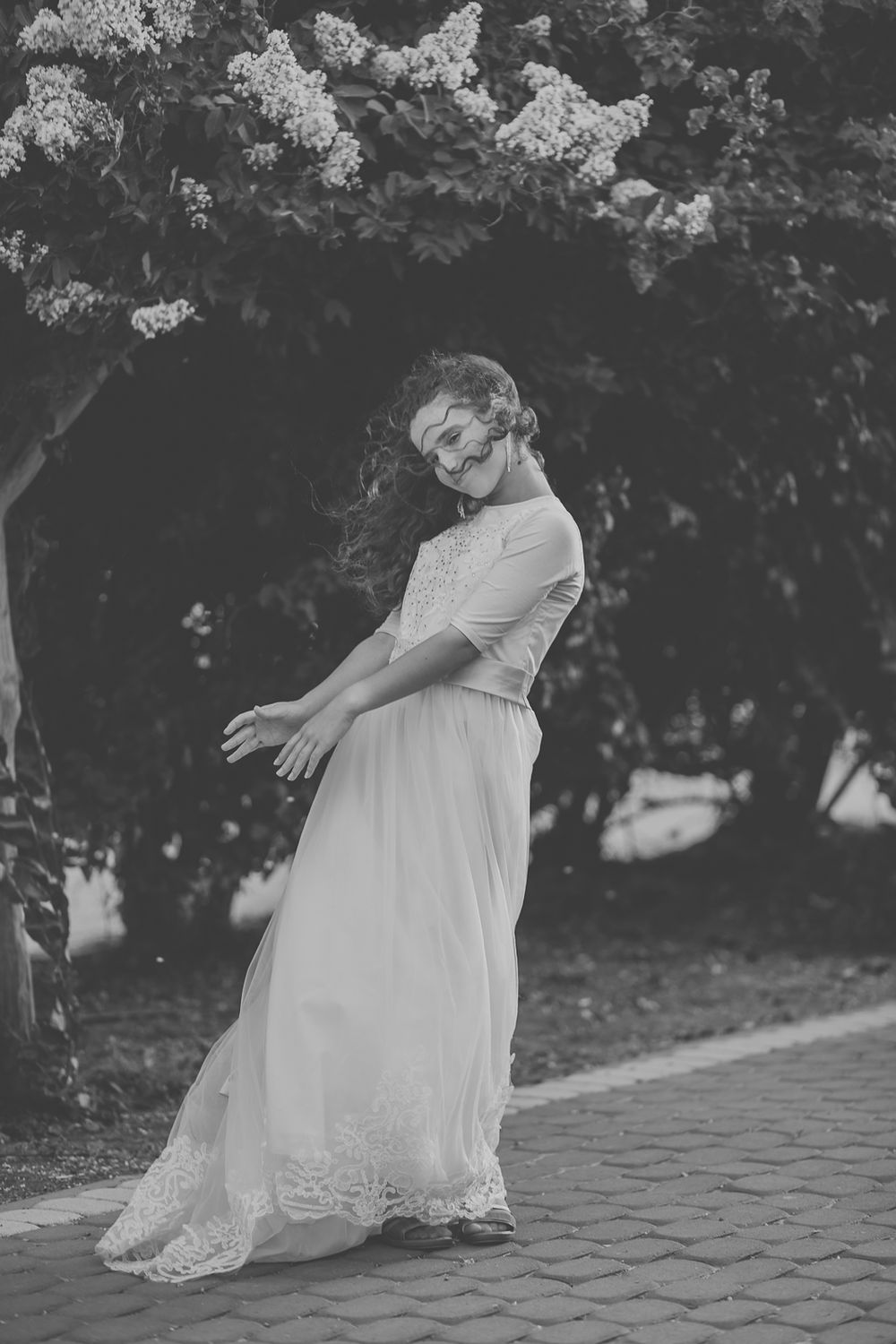 a black and white picture of a beautiful girl standing next to flowers