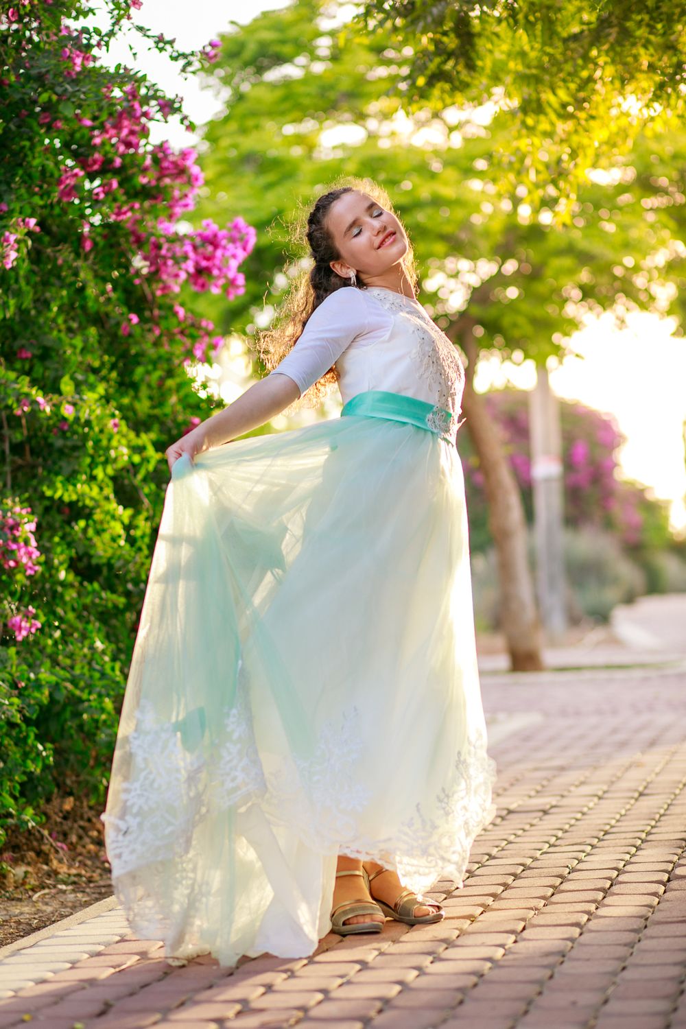 A girl stands in the path and shows off her dress