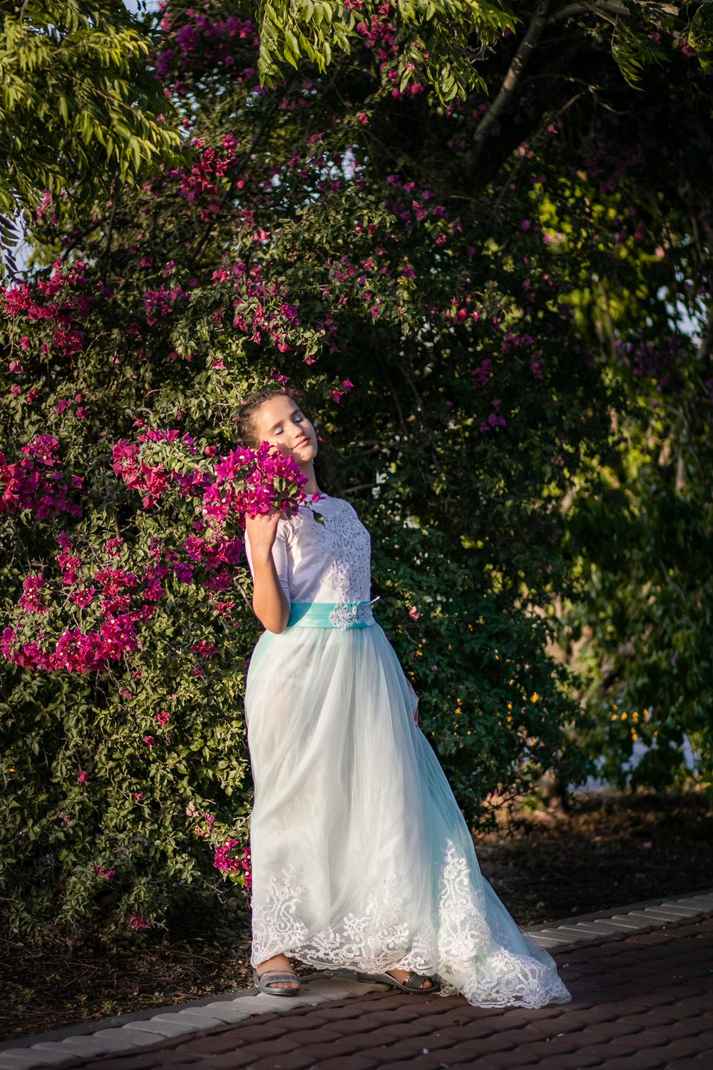 A beautiful girl stands next to flowers
