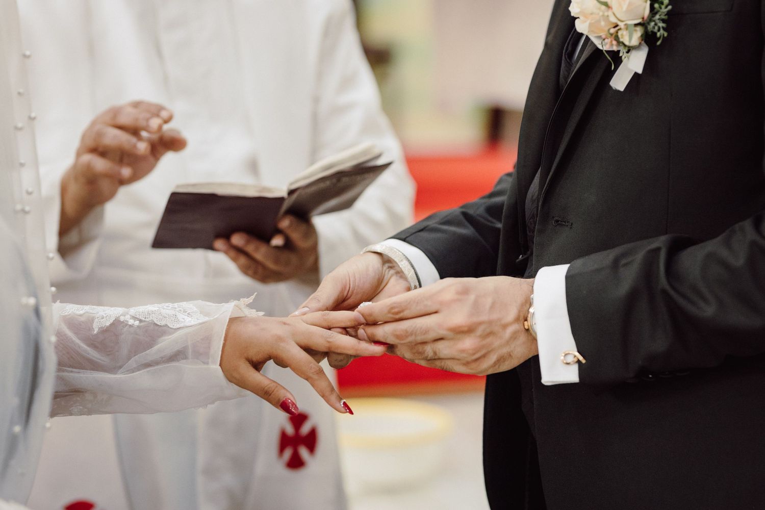 Close-up of hands during wedding ceremony proceedings in formal attire.