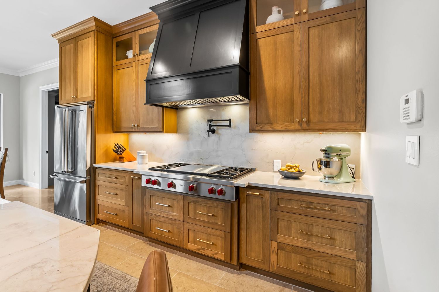 Modern kitchen with wooden cabinets, stainless appliances, and black range hood.