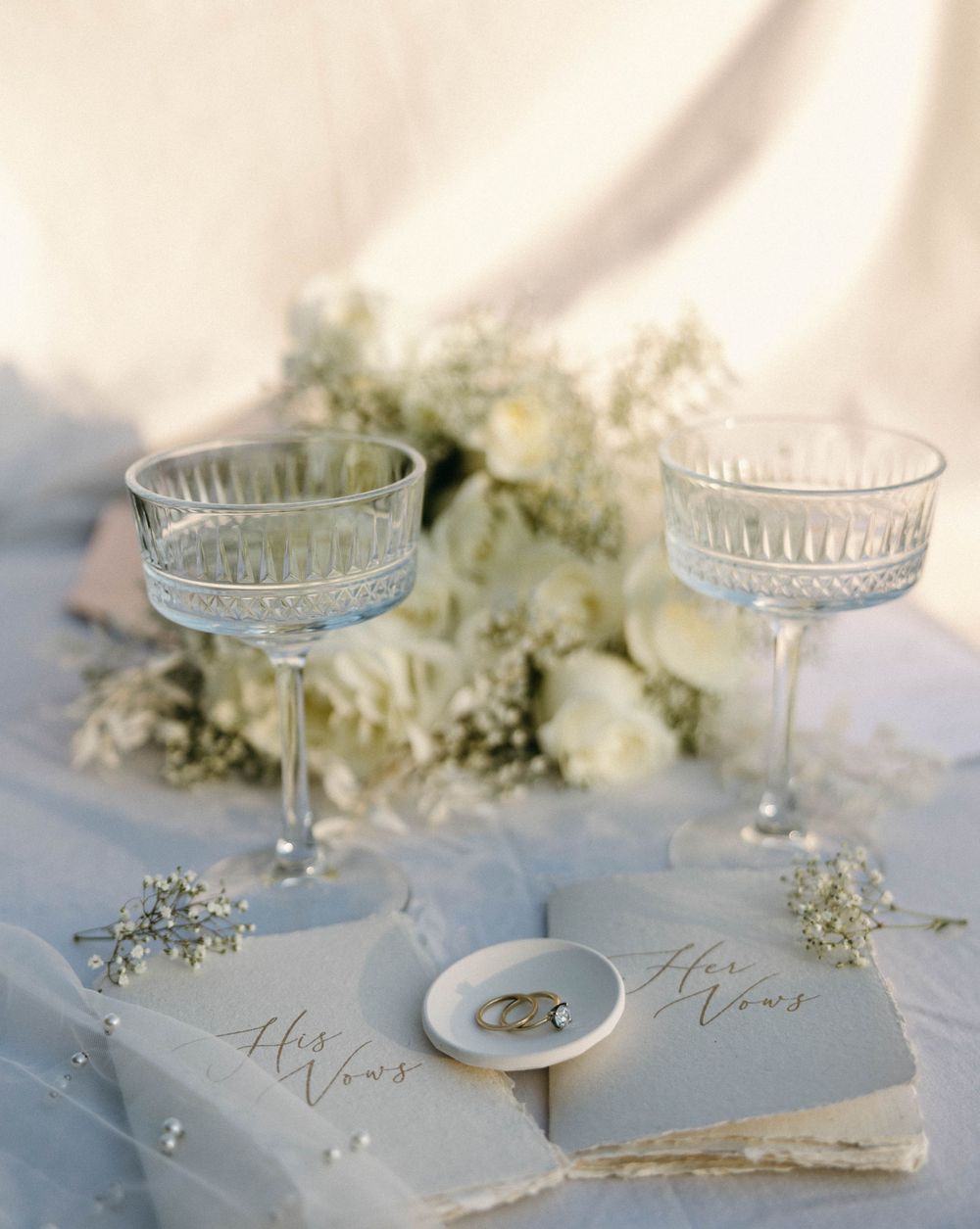 Elegant wedding table setting with crystal glasses, white flowers and handwritten name cards.