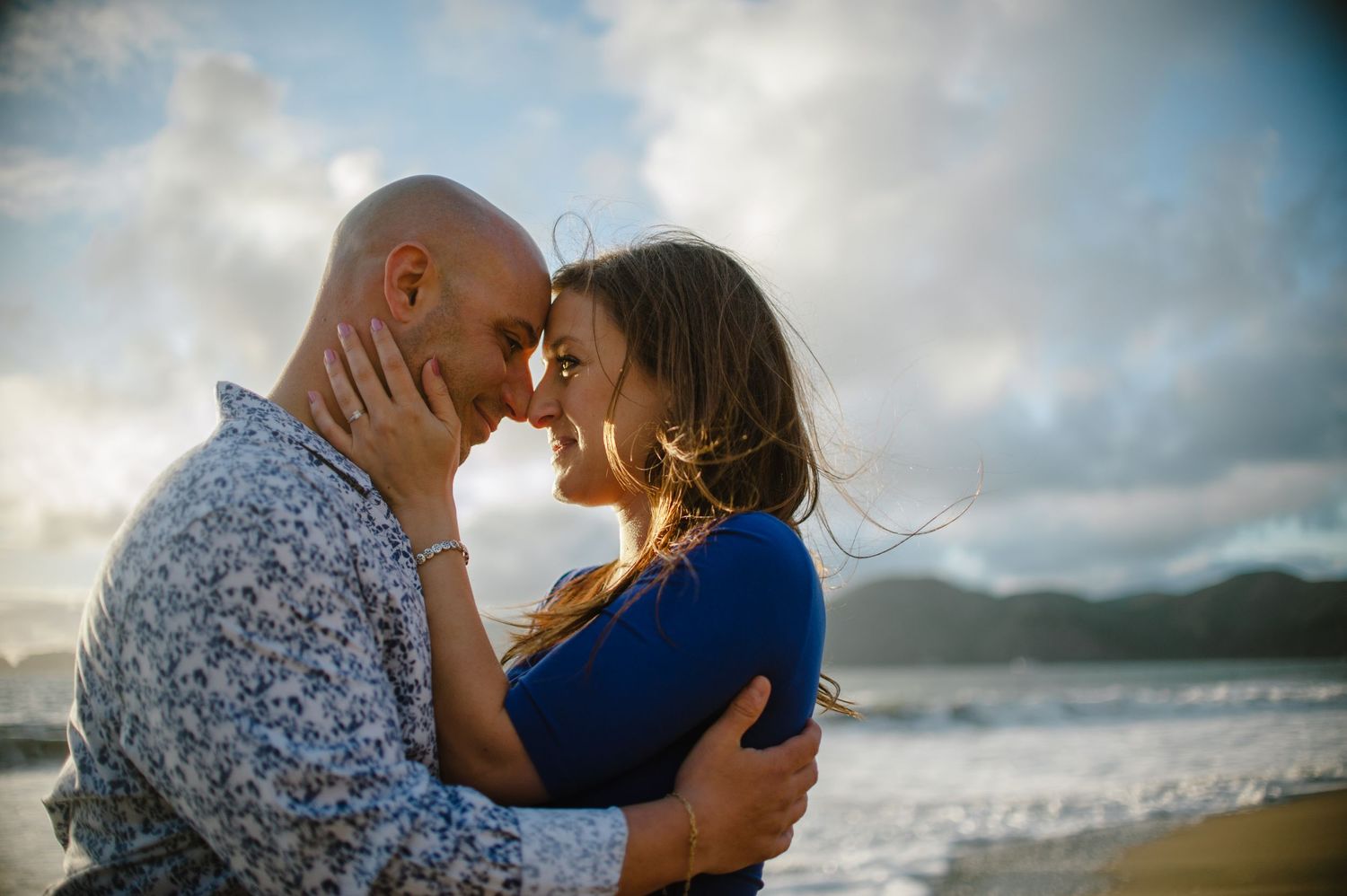 A romantic beach moment with mountains and the Golden Gate Bridge in the background.