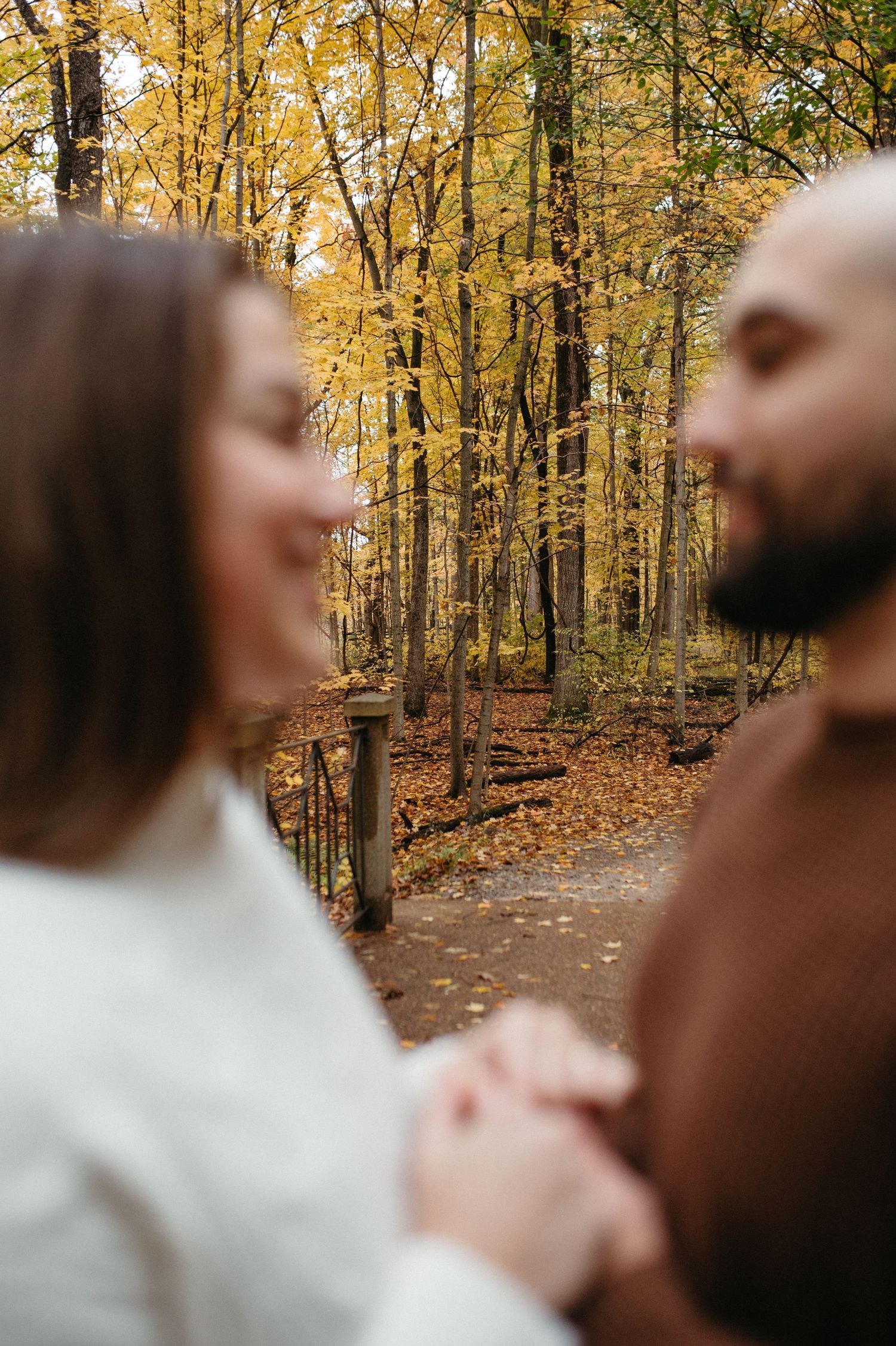 A couple shares a joyful moment together in an autumn forest with golden yellow leaves.