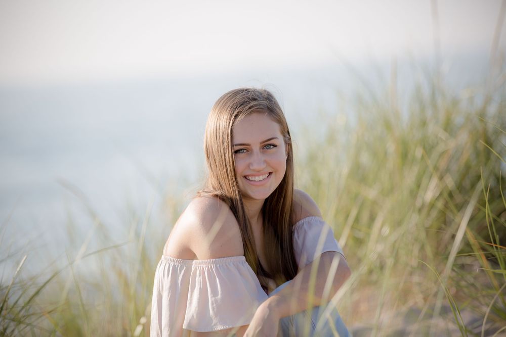 Portrait in beach grass wearing off-shoulder top during golden hour.