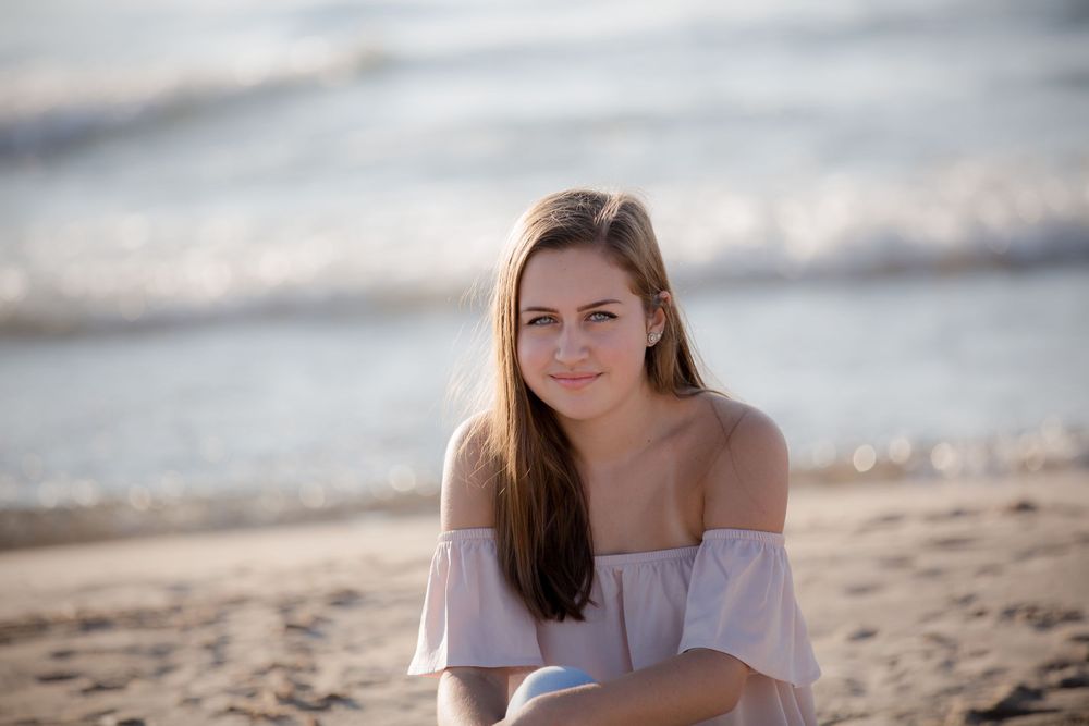 Beach portrait with off-shoulder top and natural lighting.