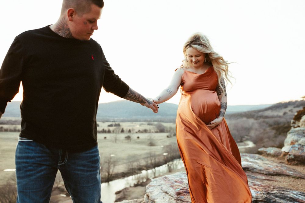 A couple shares a romantic moment on a clifftop in warm evening light.
