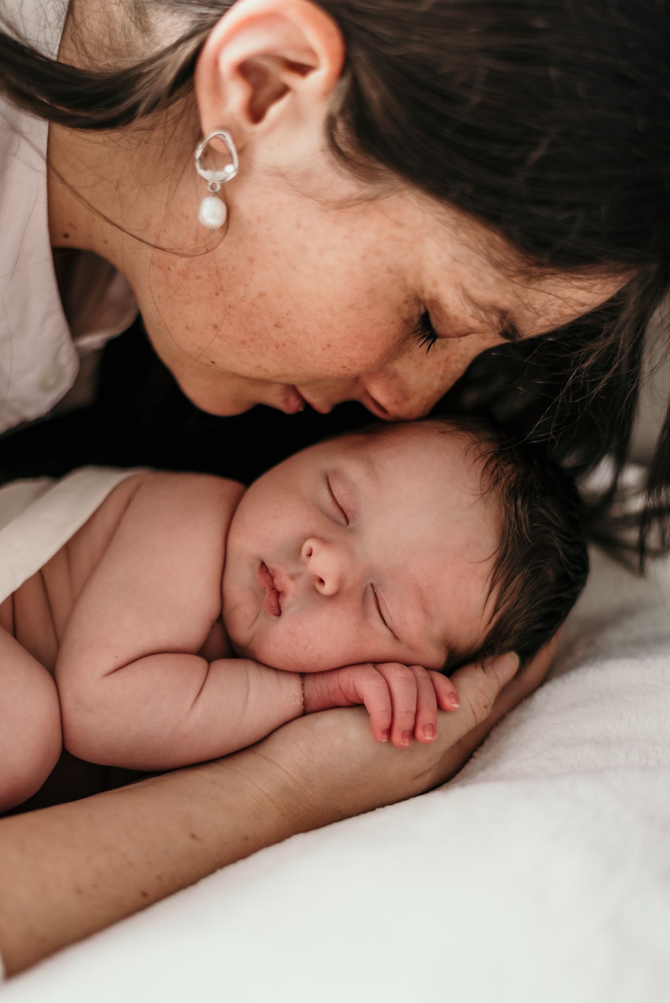 Intimate portrait of tender moment between parent and sleeping baby.