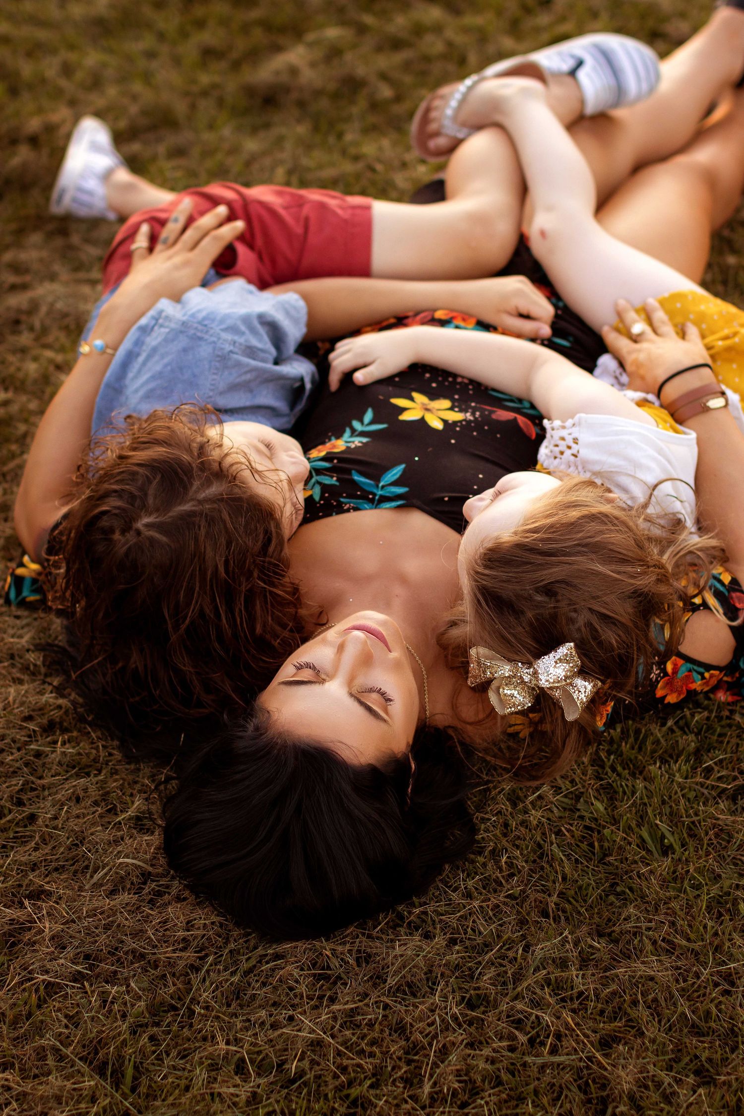 mother laying in grass hugging her two children