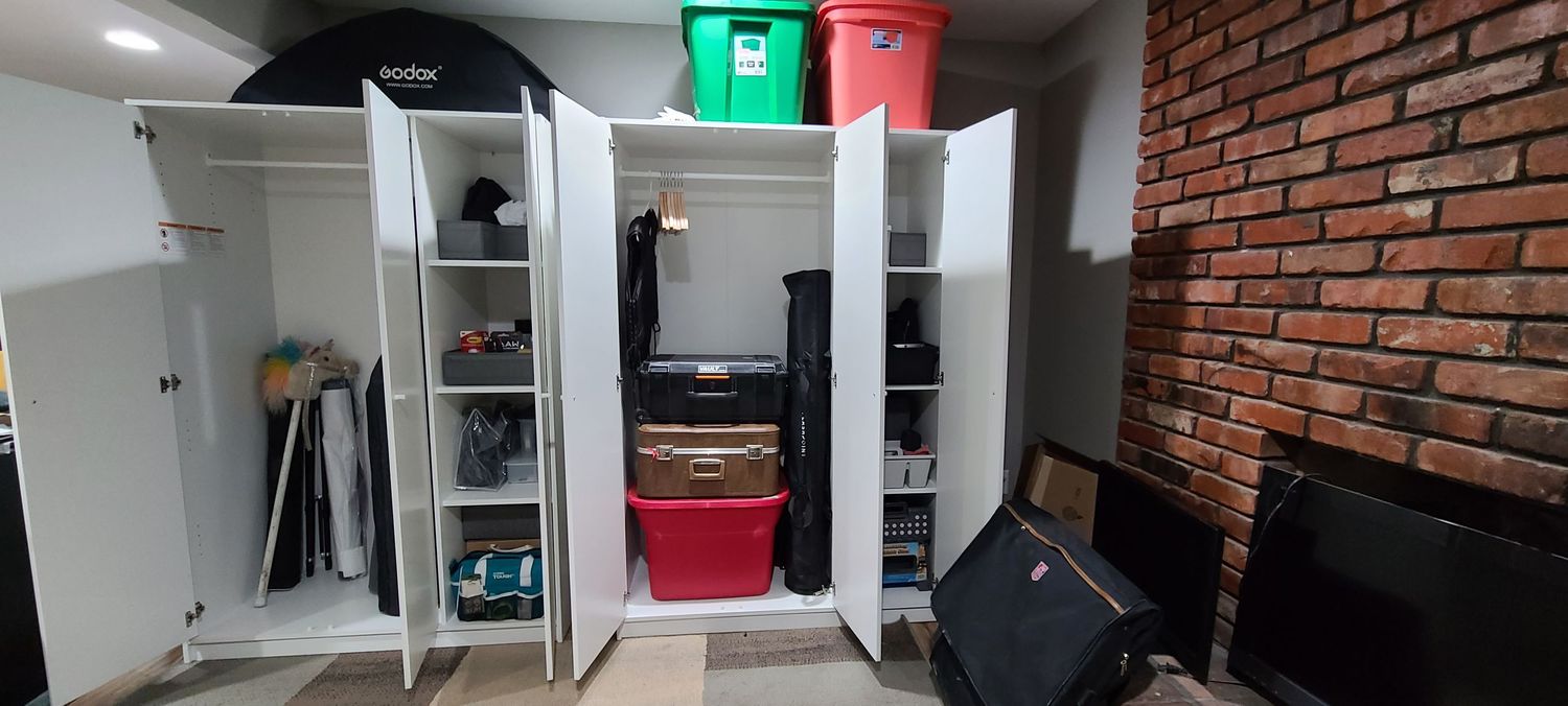 Storage cabinets and shelving units against exposed brick wall in interior room with white lighting.