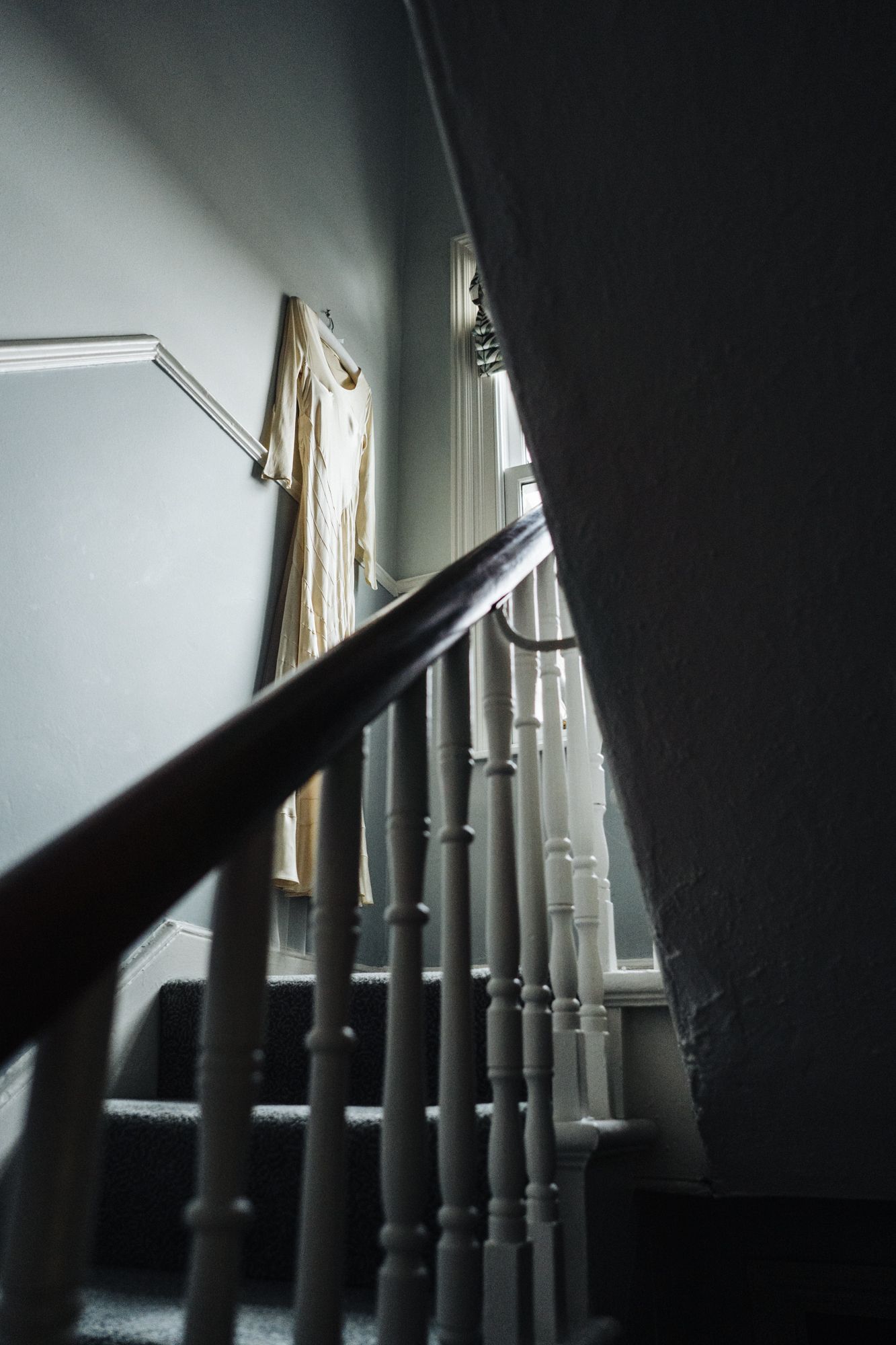 Dramatic view up a white painted staircase with natural light streaming through a window.