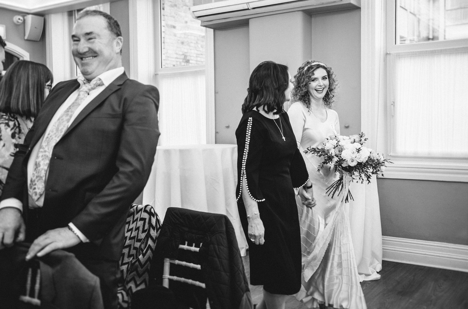 A black and white candid moment captured during an indoor wedding ceremony.