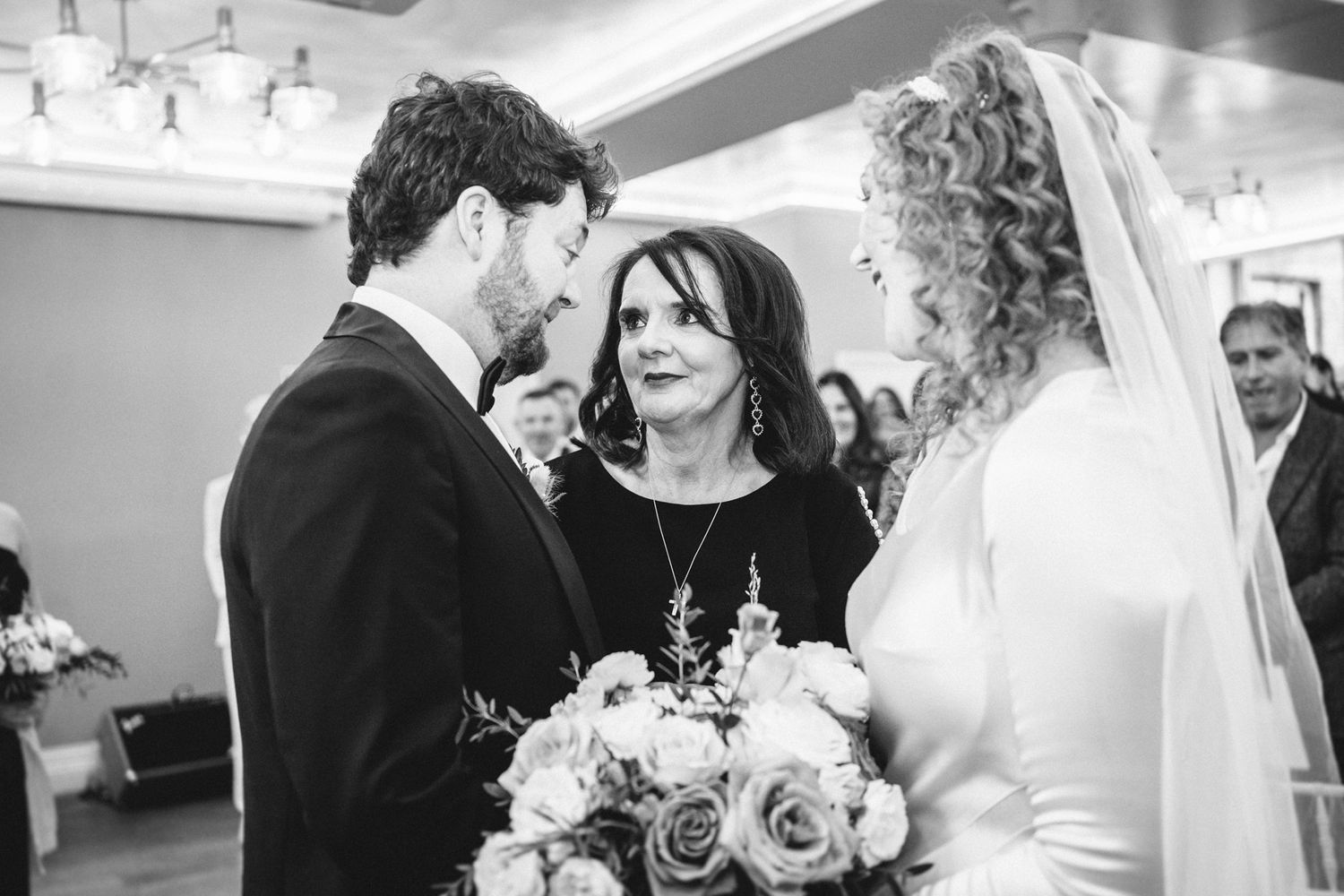 An intimate black and white moment captured during an indoor wedding ceremony.