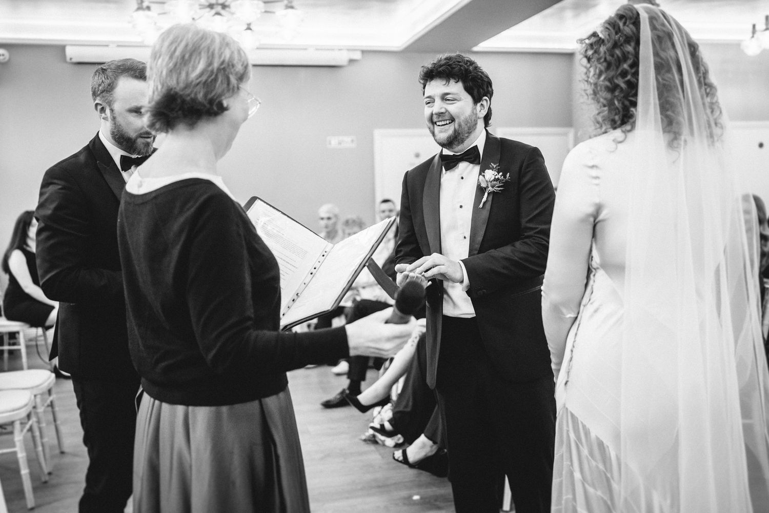 Black and white photo of a wedding ceremony with an officiant reading from a book.