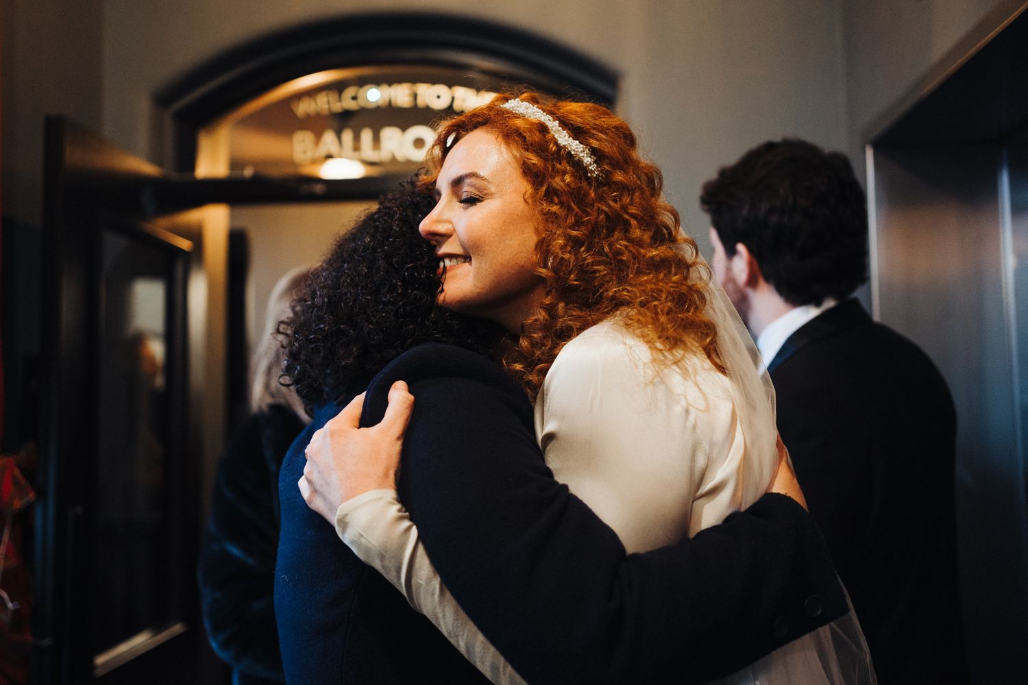 Two people share an emotional embrace at a wedding venue entrance.