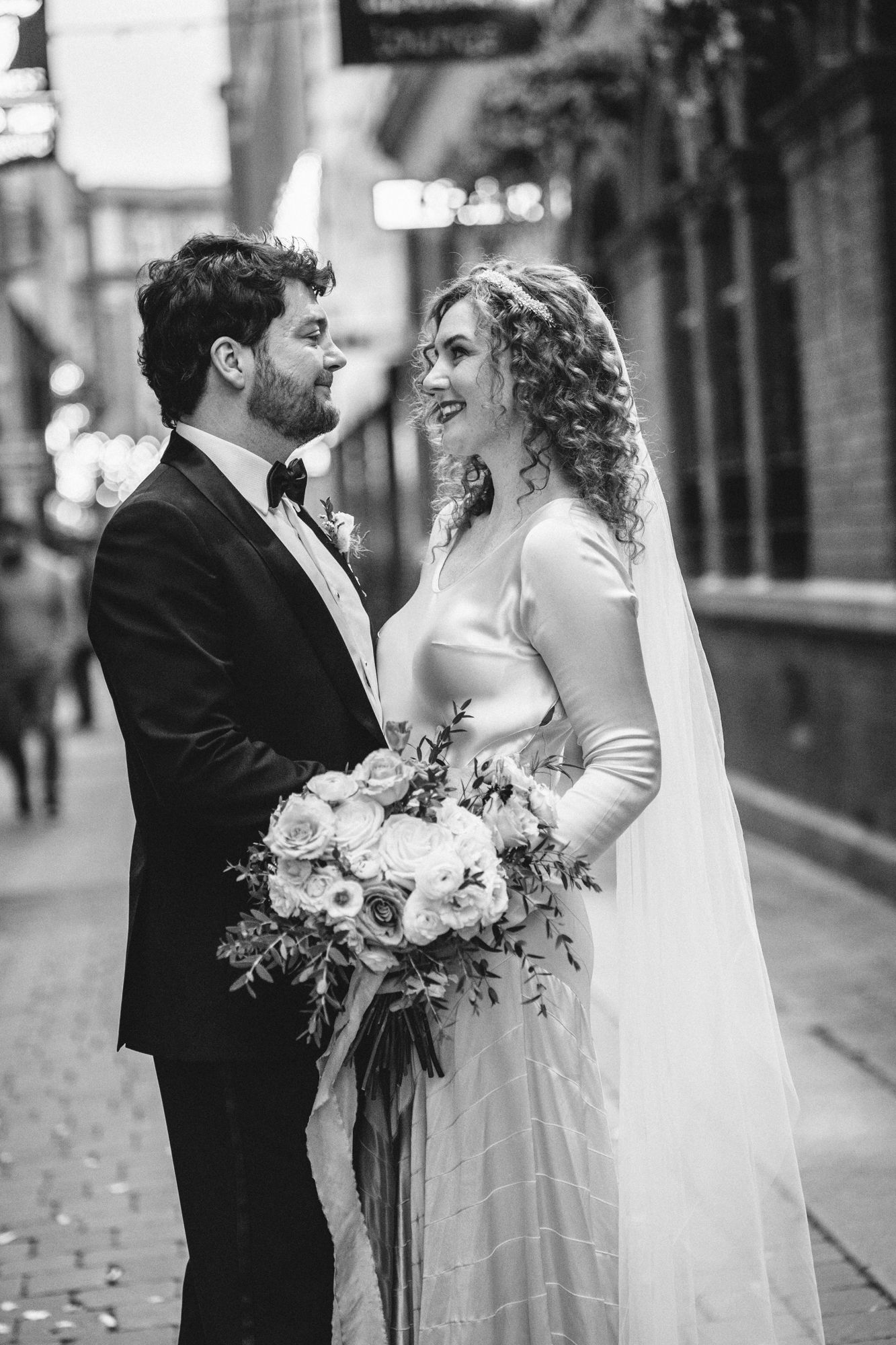 Classic black and white portrait of couple sharing intimate moment on city street.