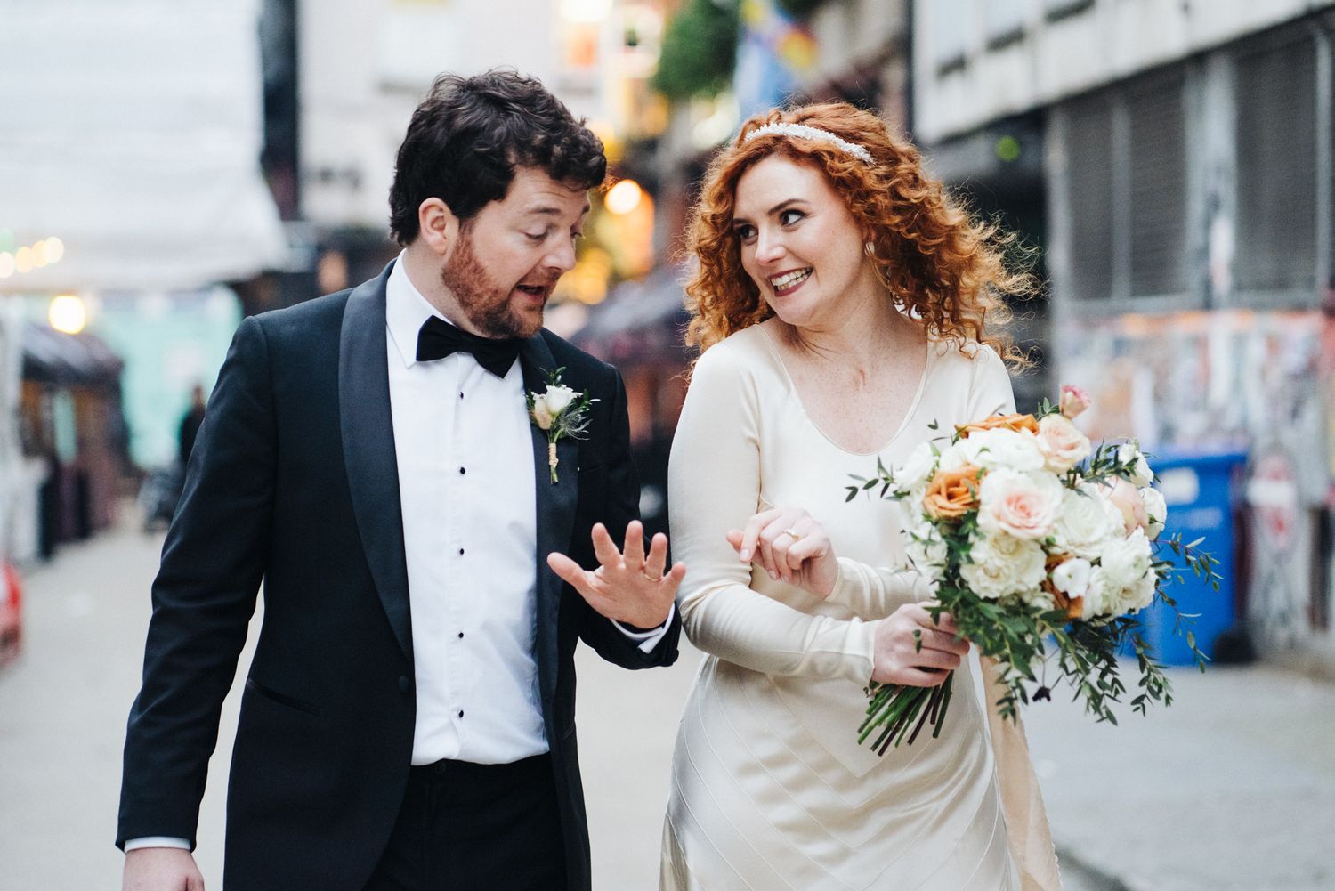 A candid moment of newlyweds laughing together on a city street during their wedding celebration.