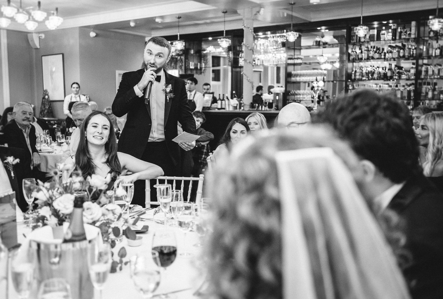 A guest delivers a speech during a formal dinner reception while others listen attentively.
