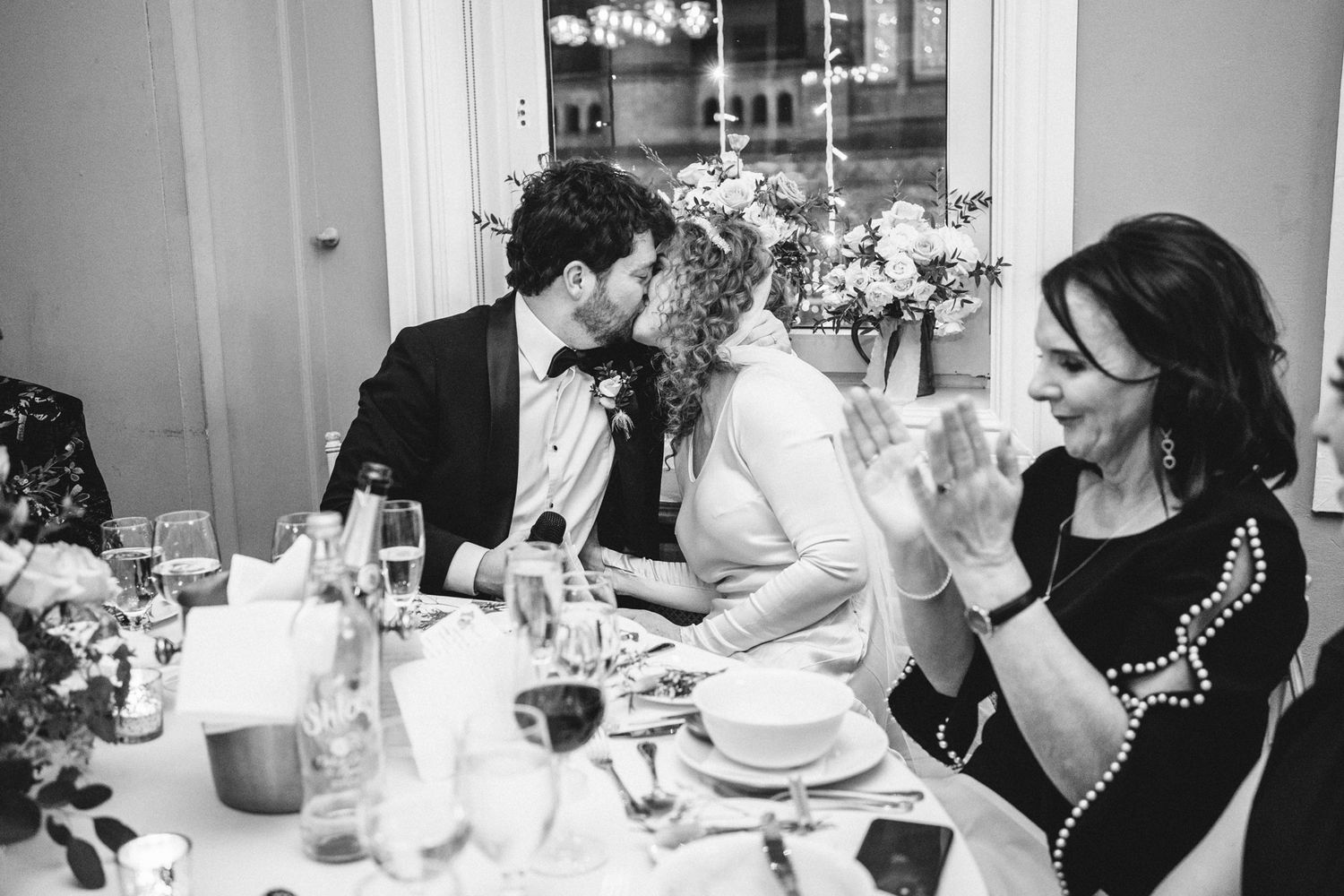 Elegant dinner party scene with guests engaged in conversation around a beautifully decorated table.