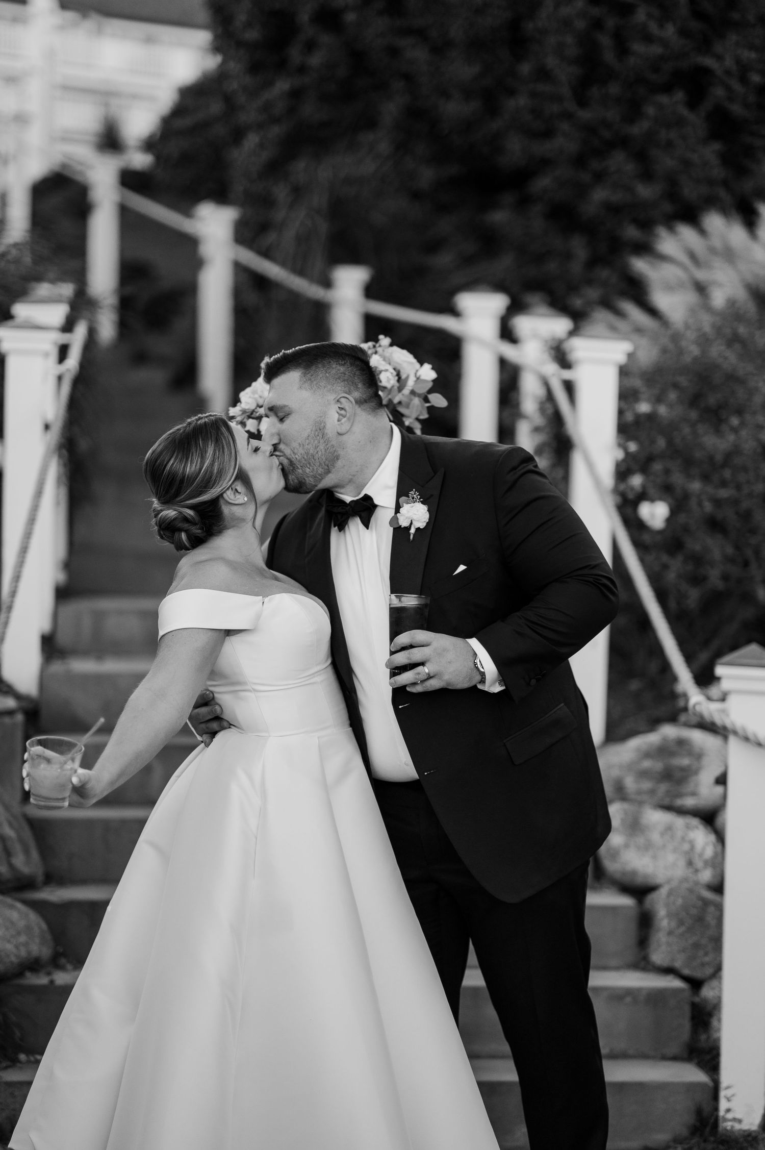 Elegant black and white wedding moment captured under white outdoor pergola.