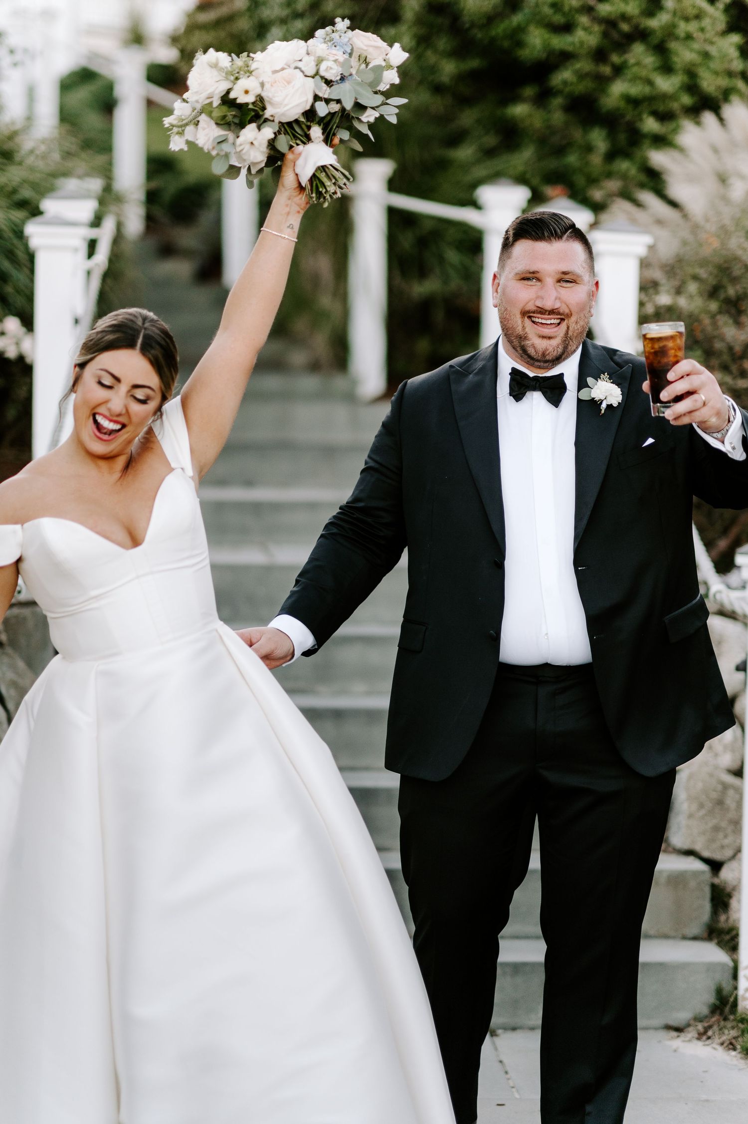 Joyful wedding celebration with couple dancing and laughing under white pergola.