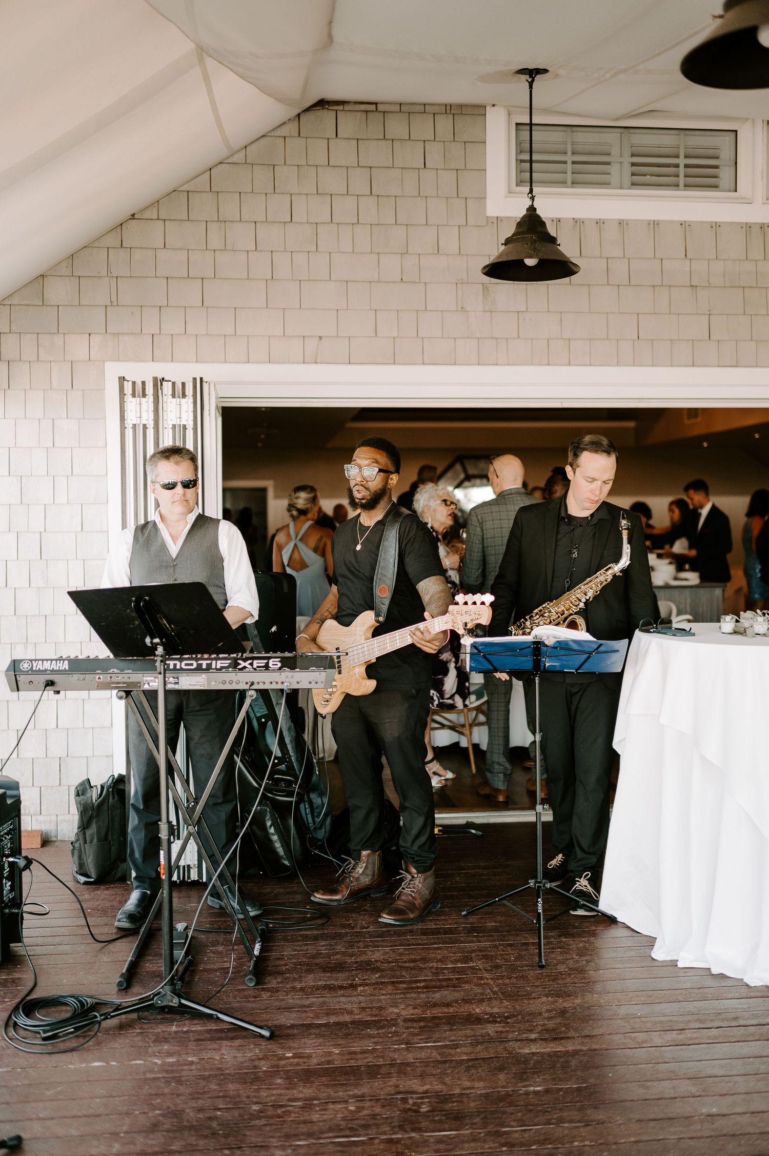 Live band performs on stage at an indoor venue with white subway tile walls.