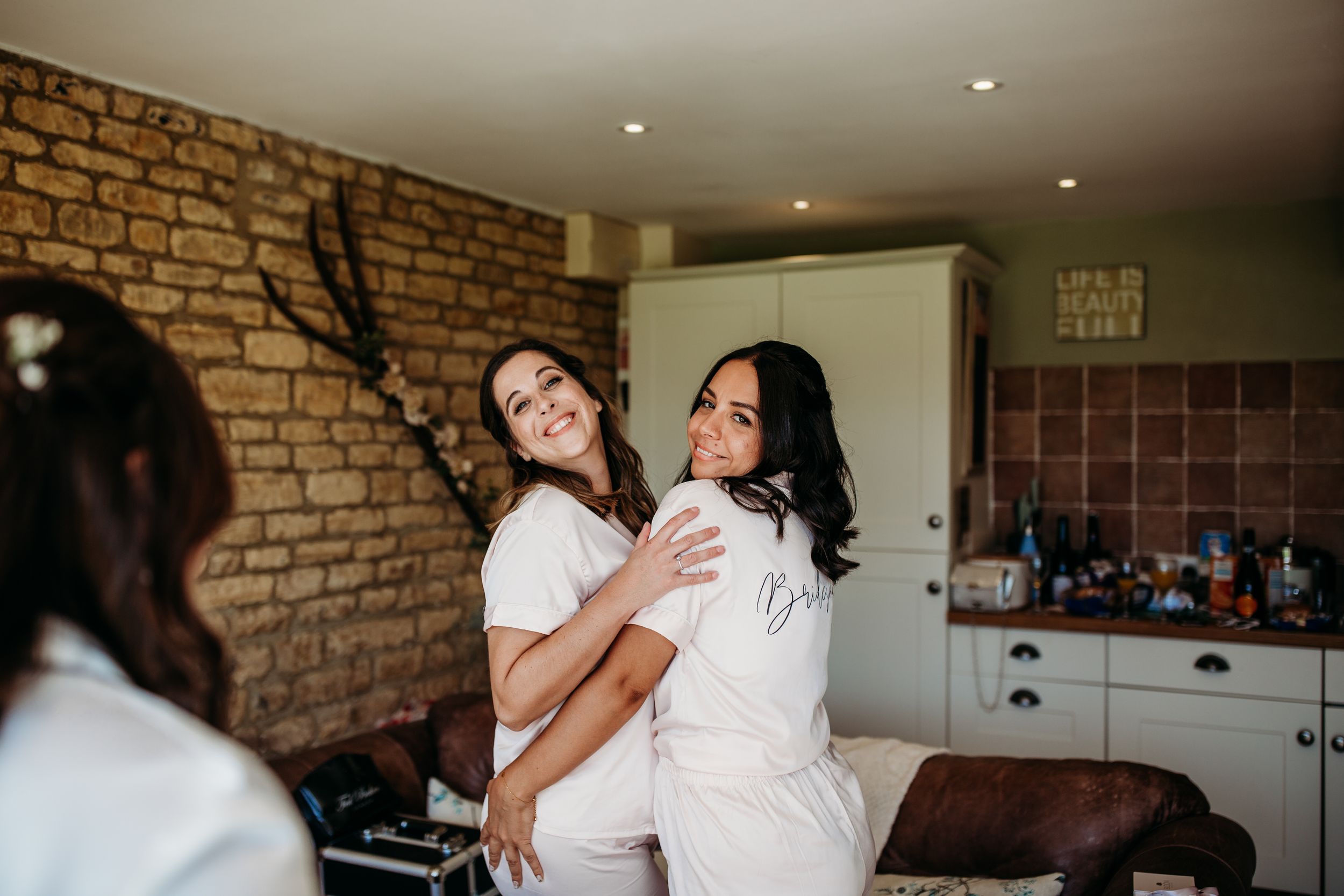 Friends in white robes having fun and dancing during pre-wedding preparations.