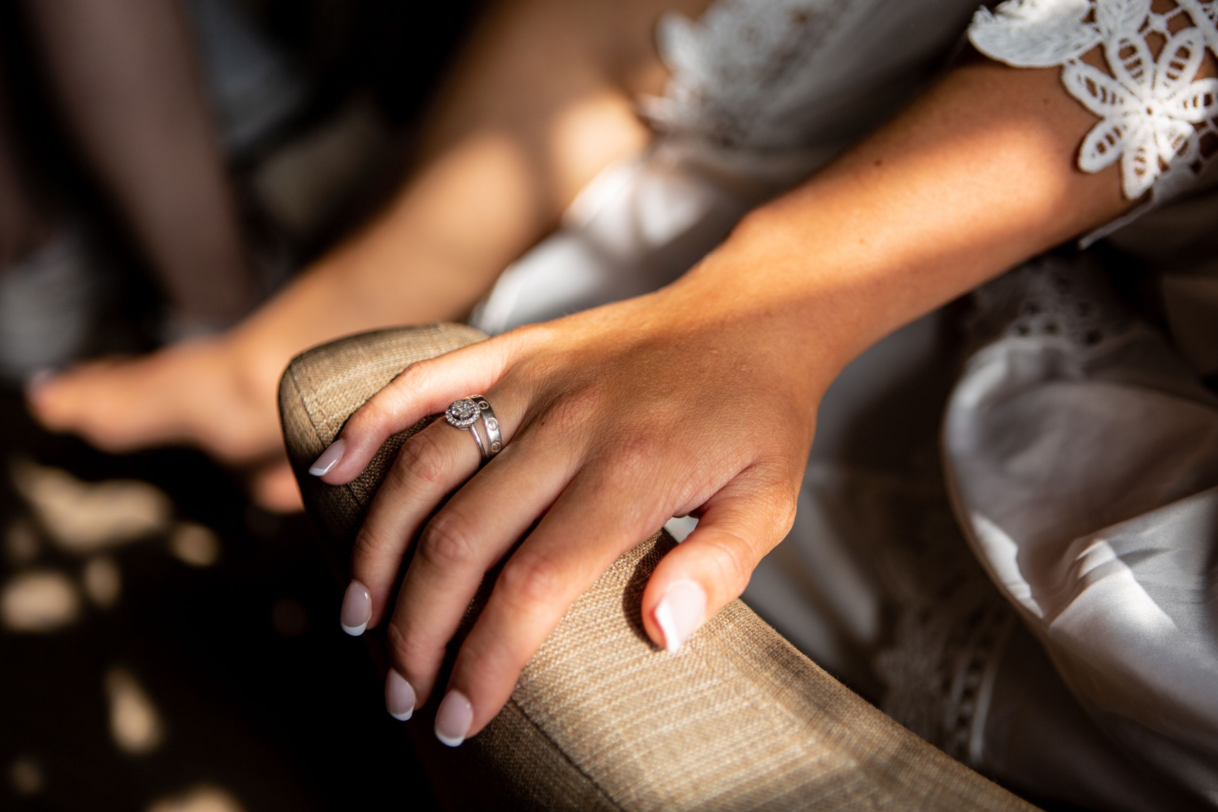 Close-up detail shot of an elegant engagement ring and wedding band on a textured surface.
