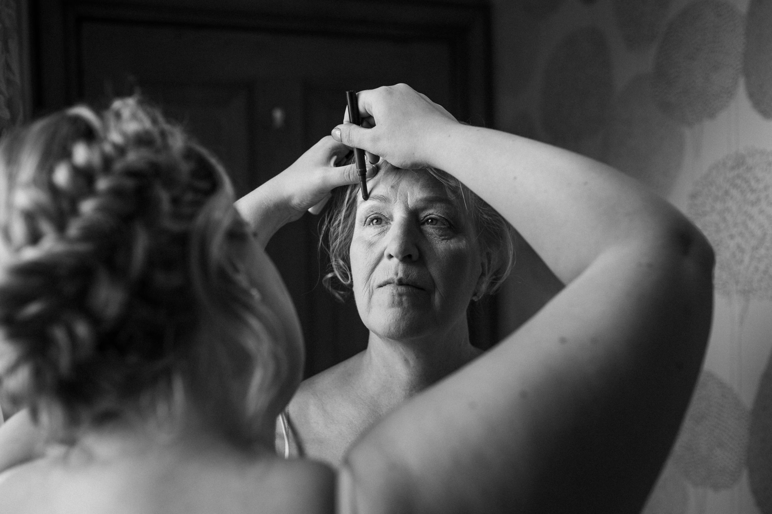 Black and white image showing final touches being applied during wedding preparations.