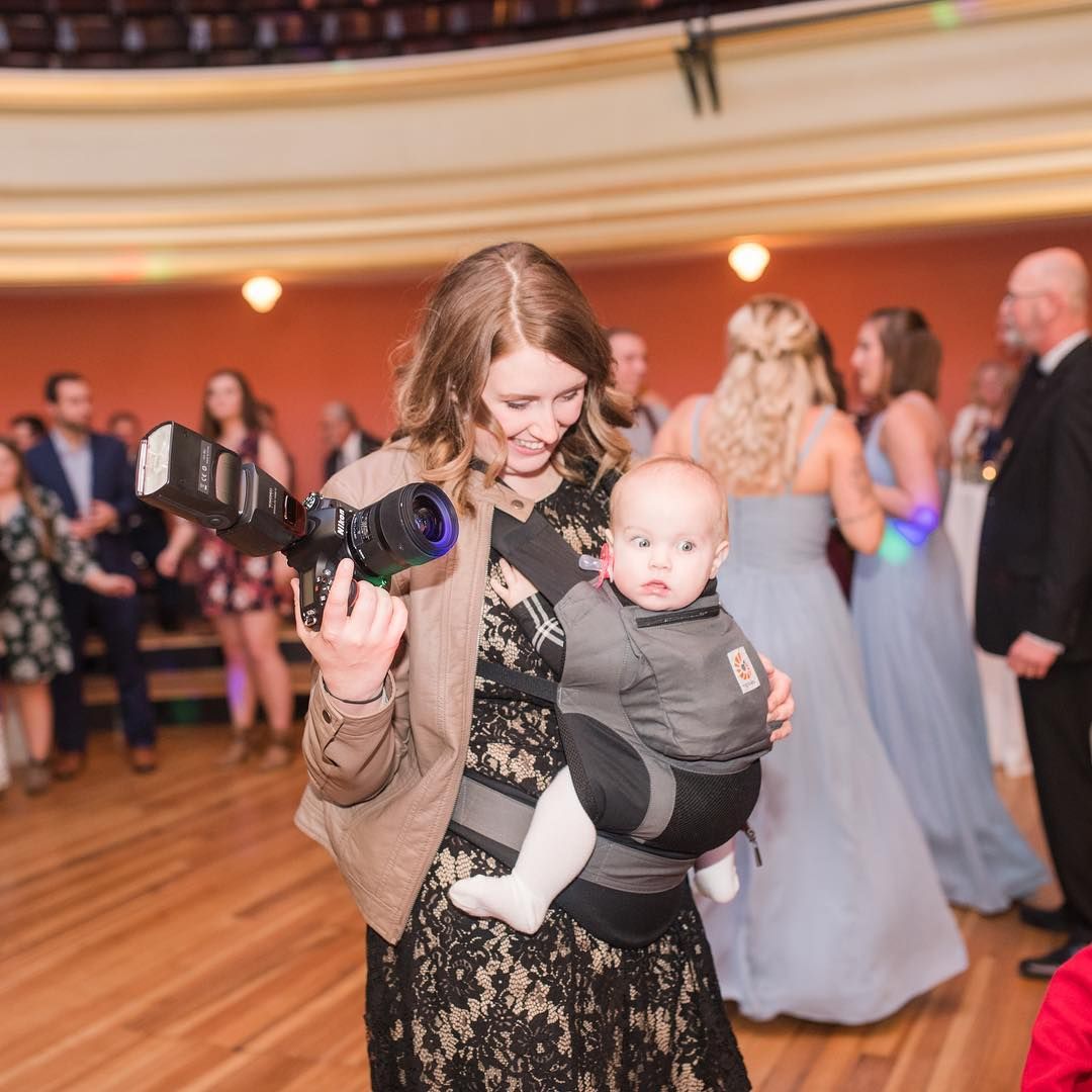 Wedding photographer capturing candid moments at a reception with guests in formal attire.