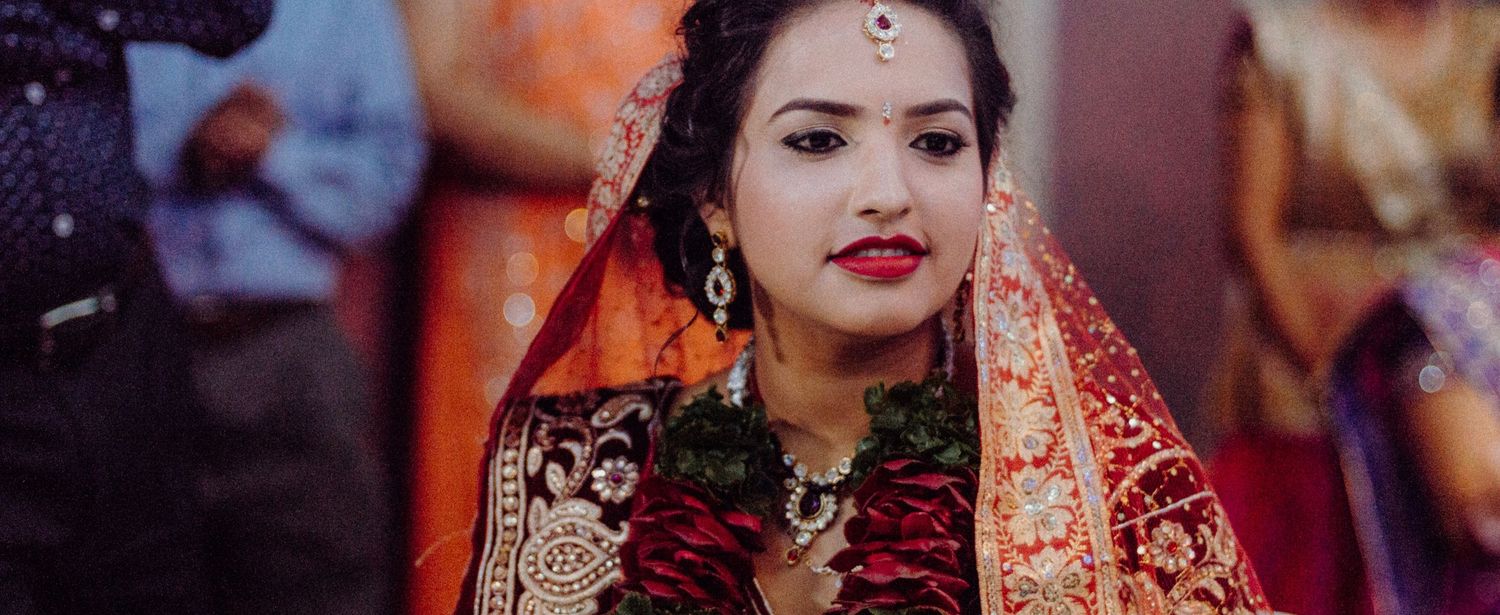 Close-up portrait of bride wearing traditional red Indian wedding attire and jewelry.