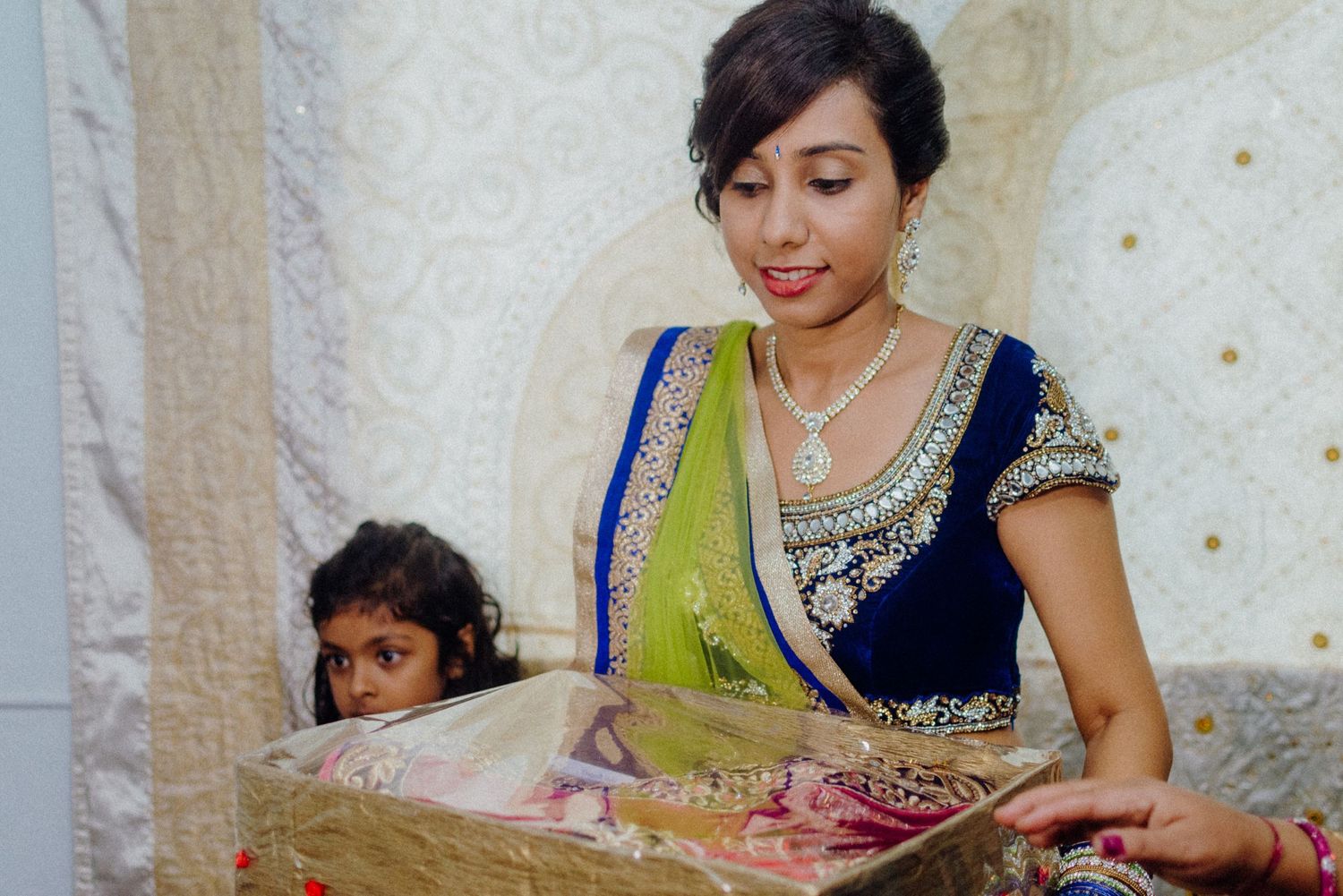 Woman in traditional Indian dress examining decorative items at wedding event.